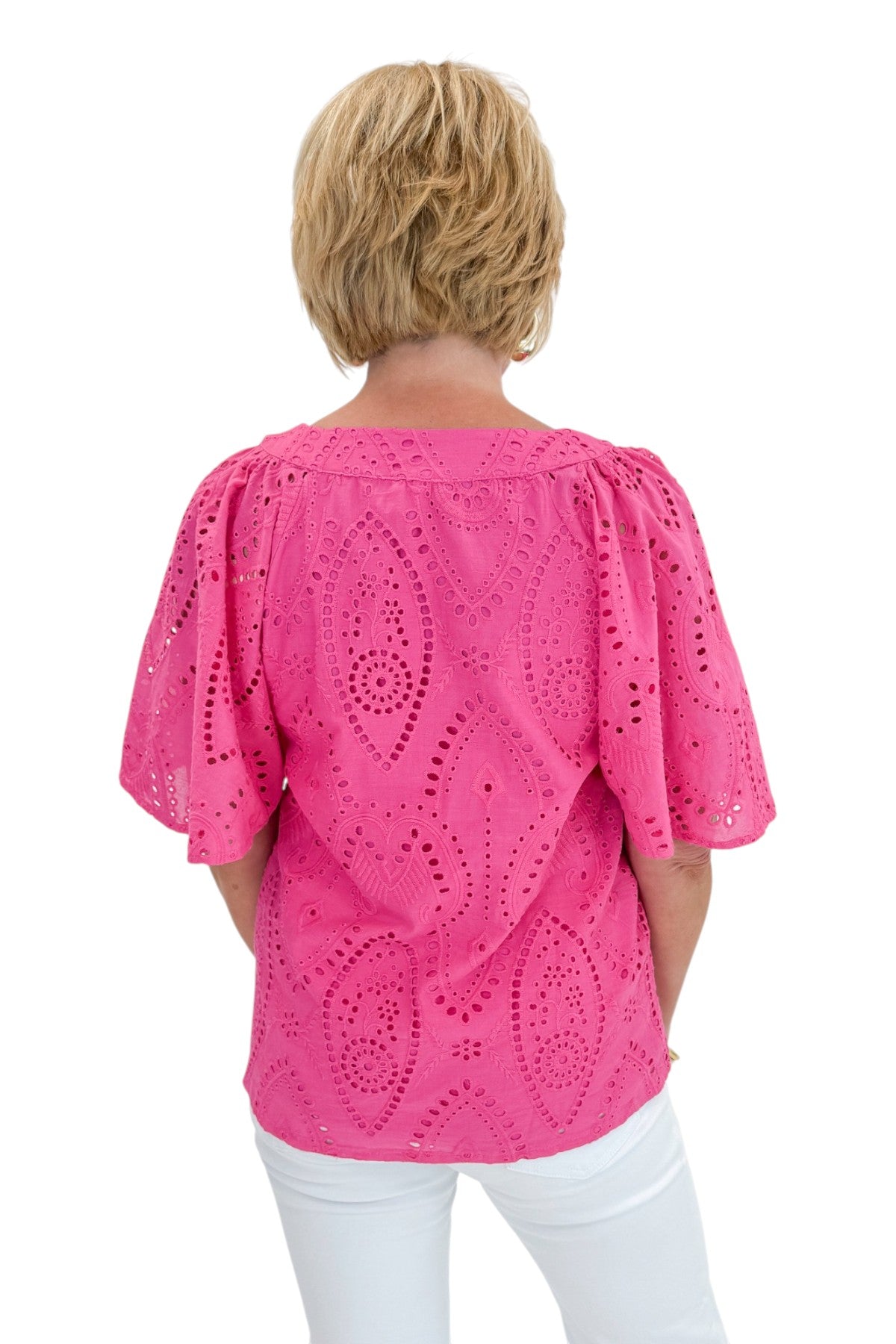Back view of woman wearing Swagger Boutiqueās Hot Pink Flutter Sleeve Eyelet Top with jeans against white studio background.