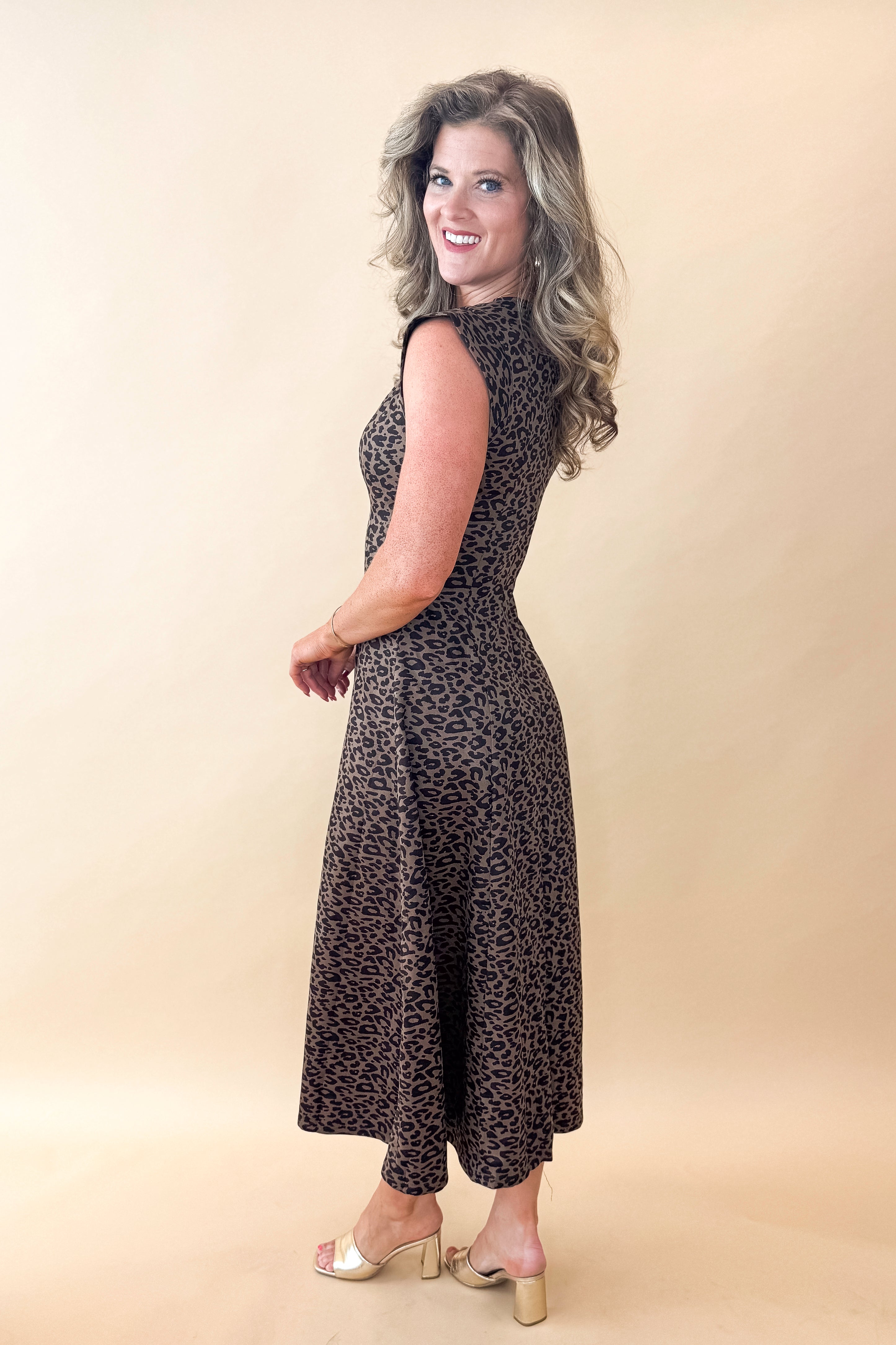 Side view of woman wearing Leopard Suede Midi Dress against tan studio background.