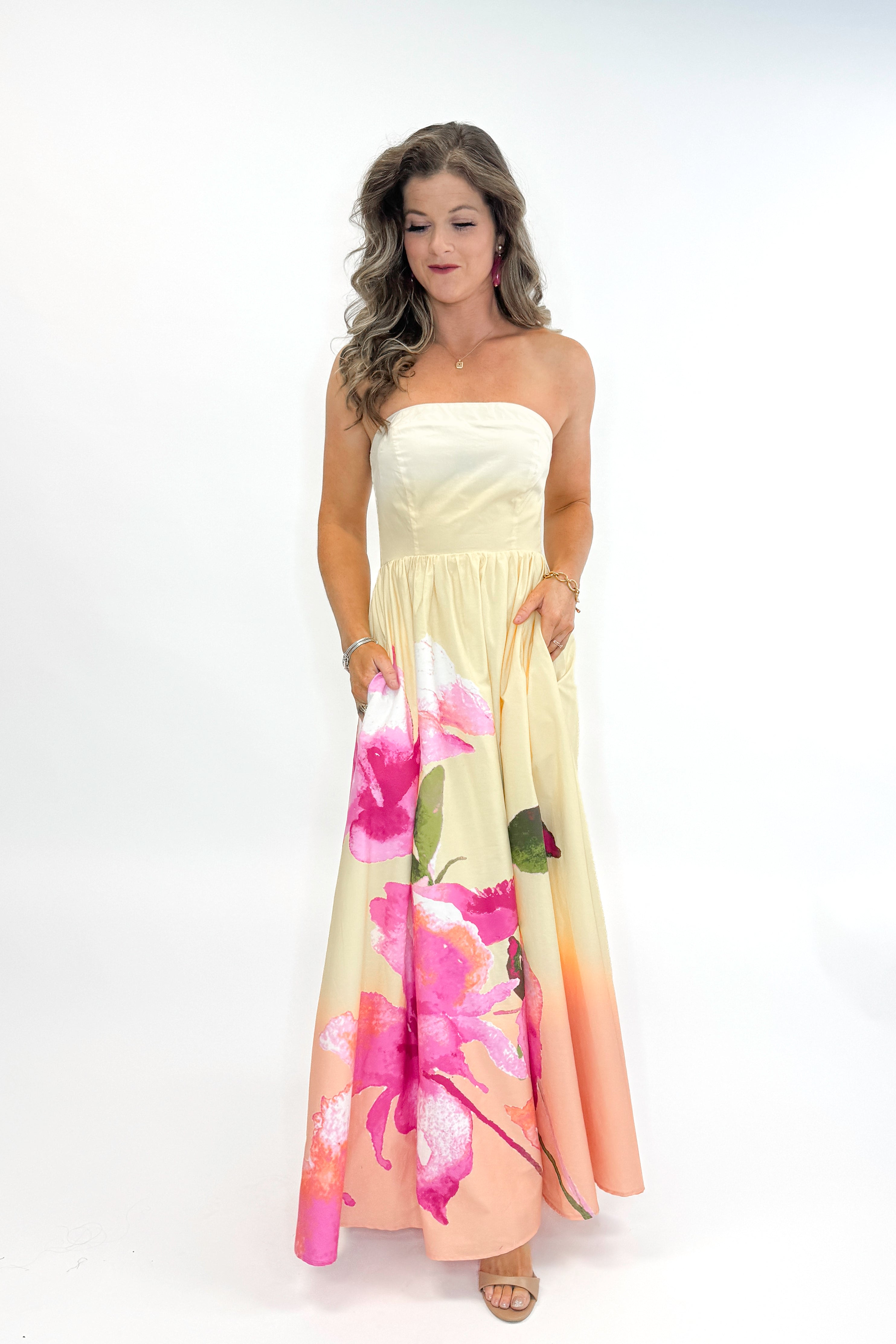 Front view of woman wearing Yellow & Pink Floral Print Strapless Maxi Dress against white studio background.