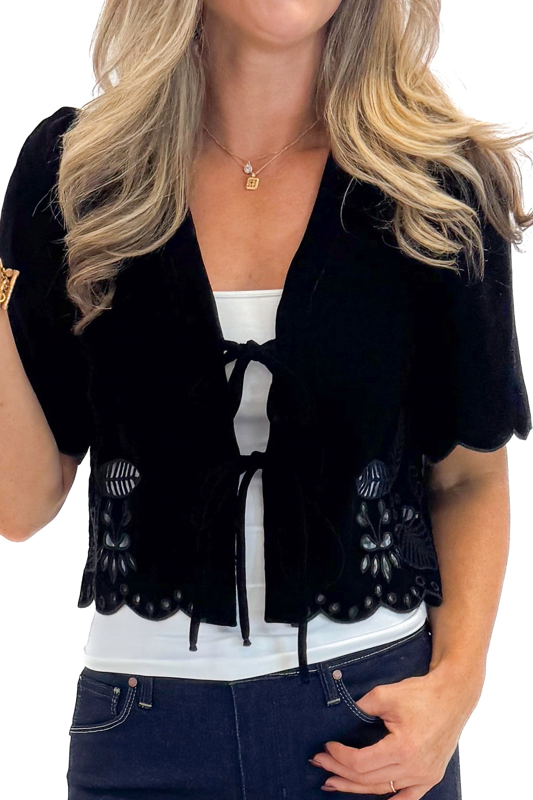 Front detail view of woman wearing Black Velvet Tie Front Top with jeans against white studio background.