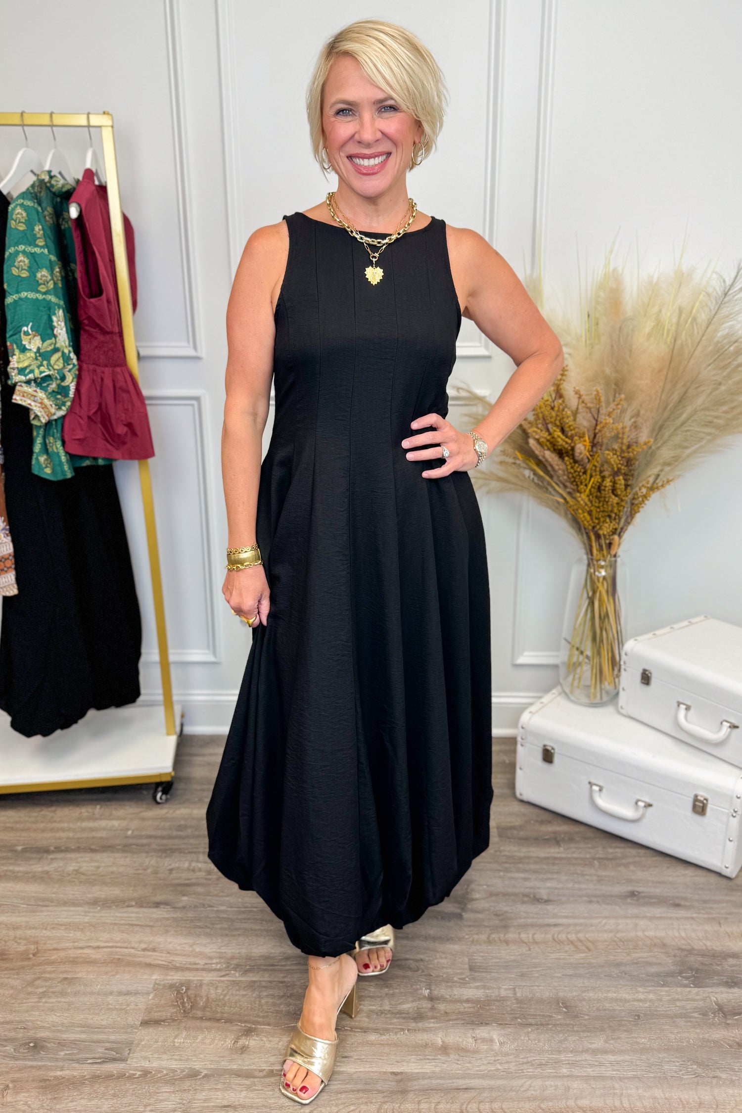 Woman wearing Black Bubble Hem Midi Dress with clothes in the background.