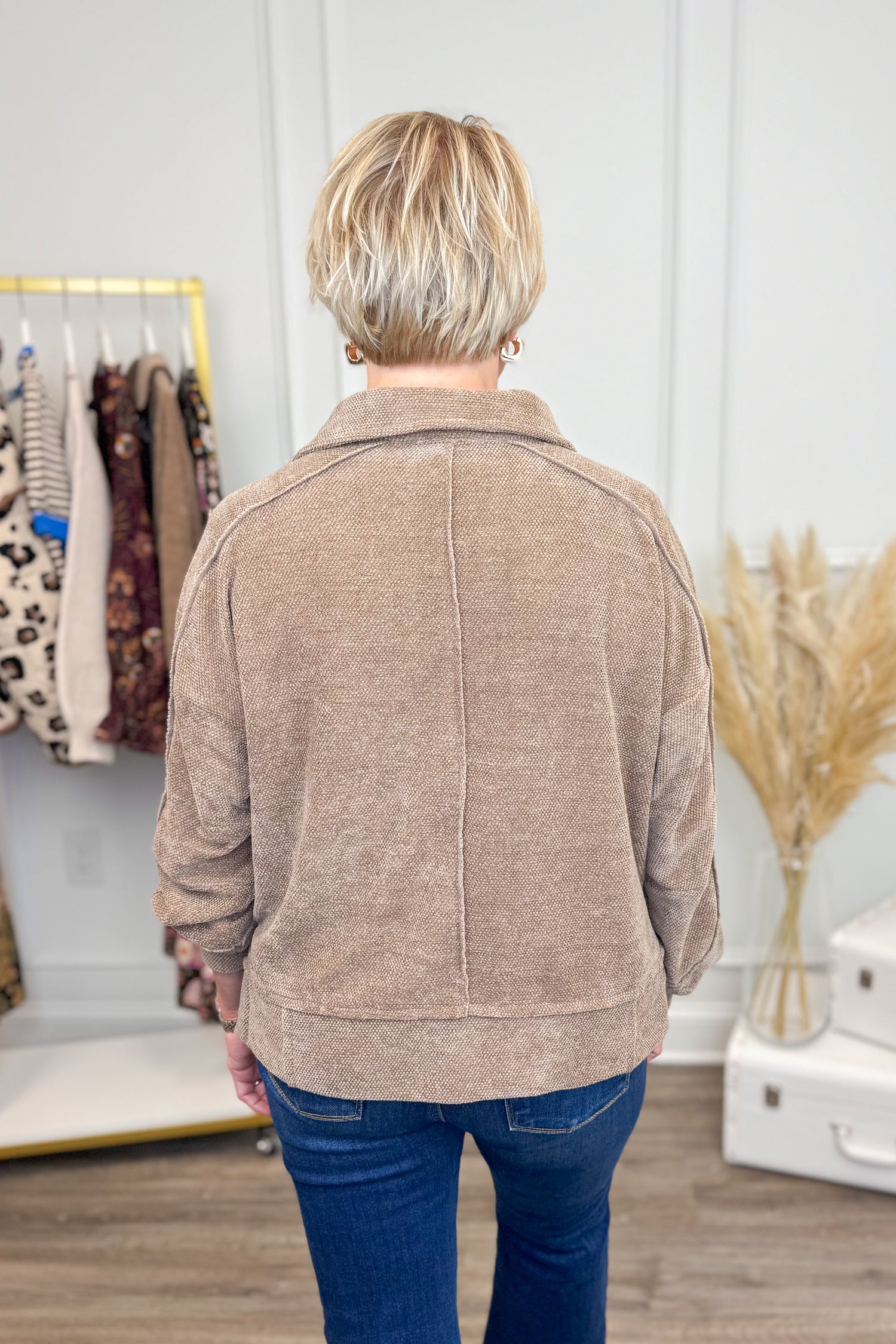 Back view of Woman wearing Mocha Chenille Collared Top and jeans with decor in the background.