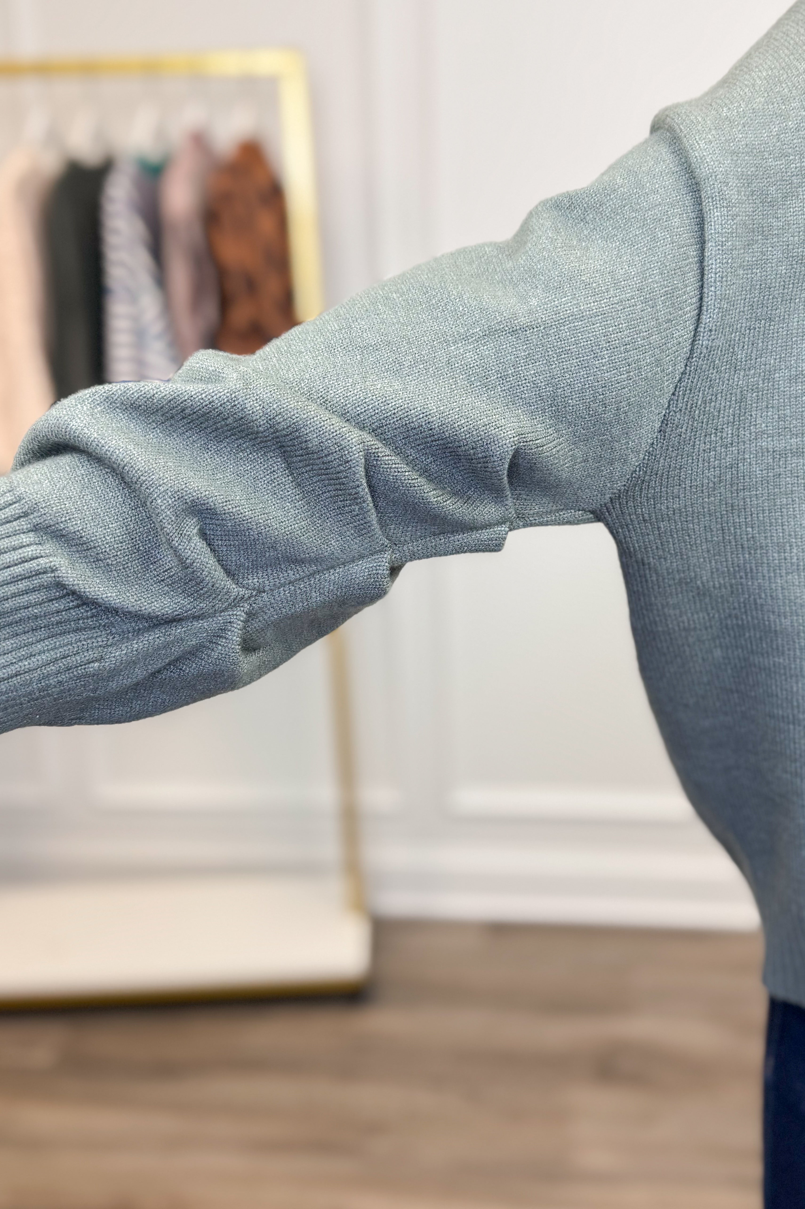 Close-up of a person wearing a green sweater with a blurred background