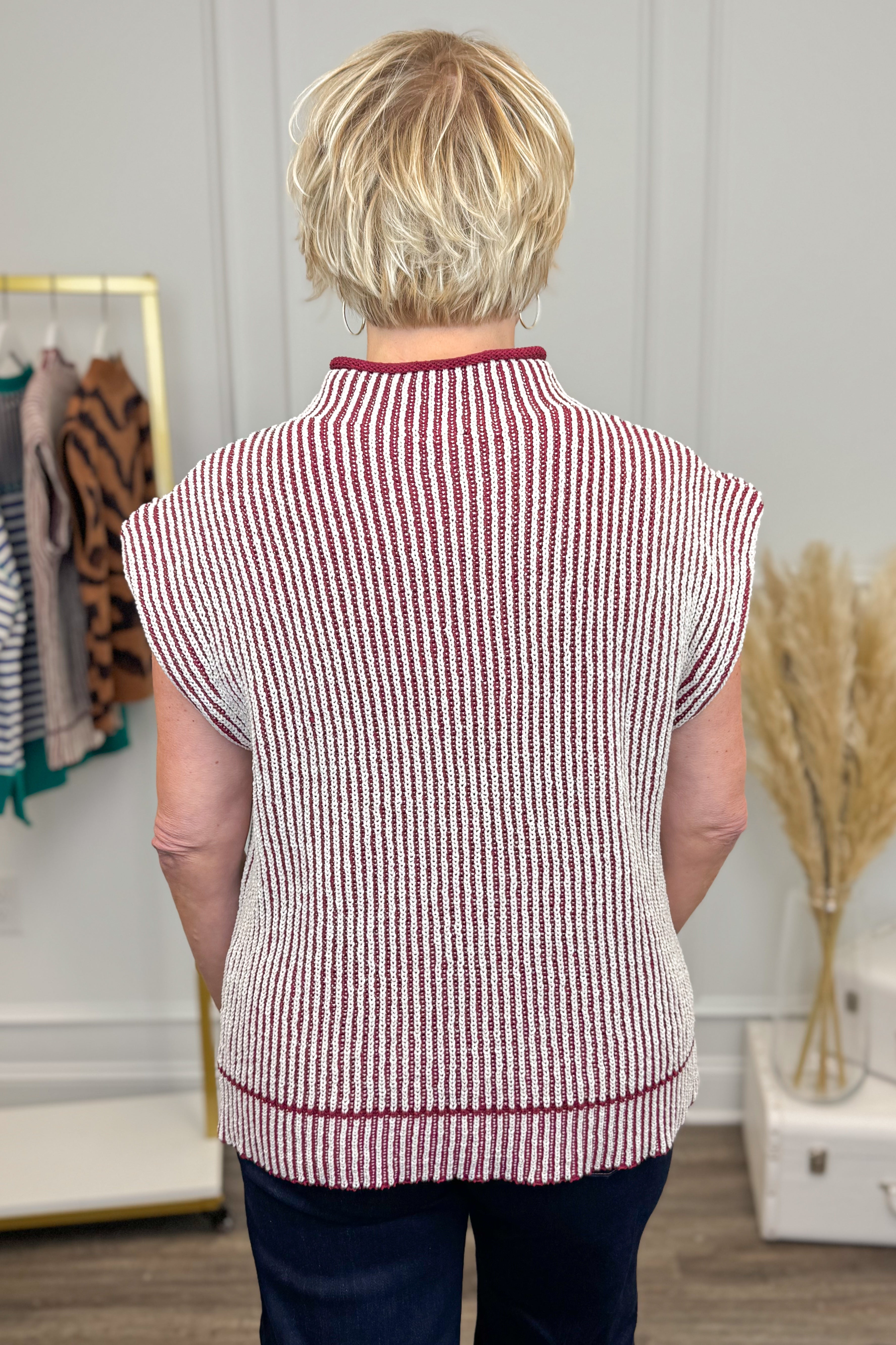 Person wearing a red and white striped vest in a room with decor elements.