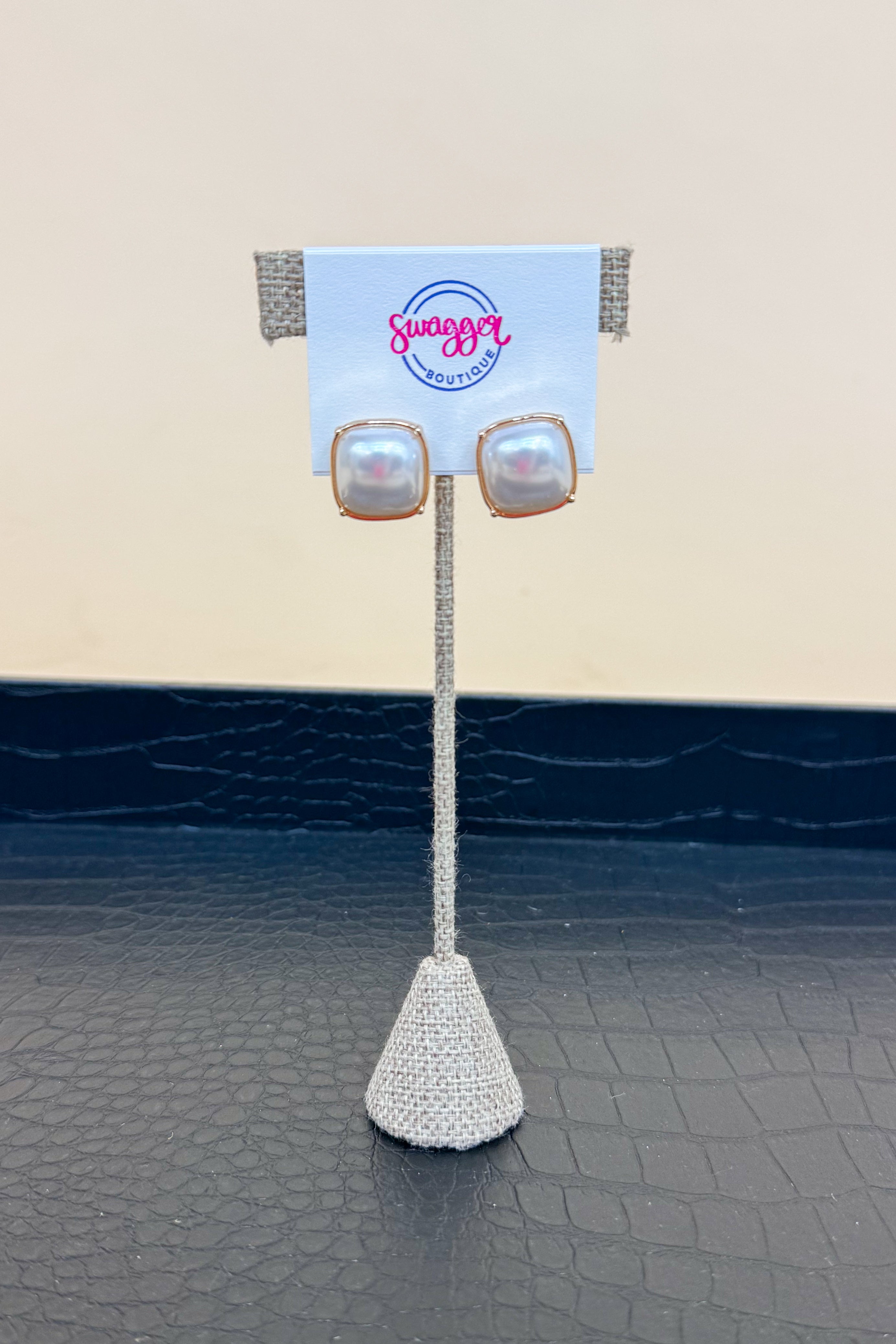 Pair of pearl earrings on a stand with &