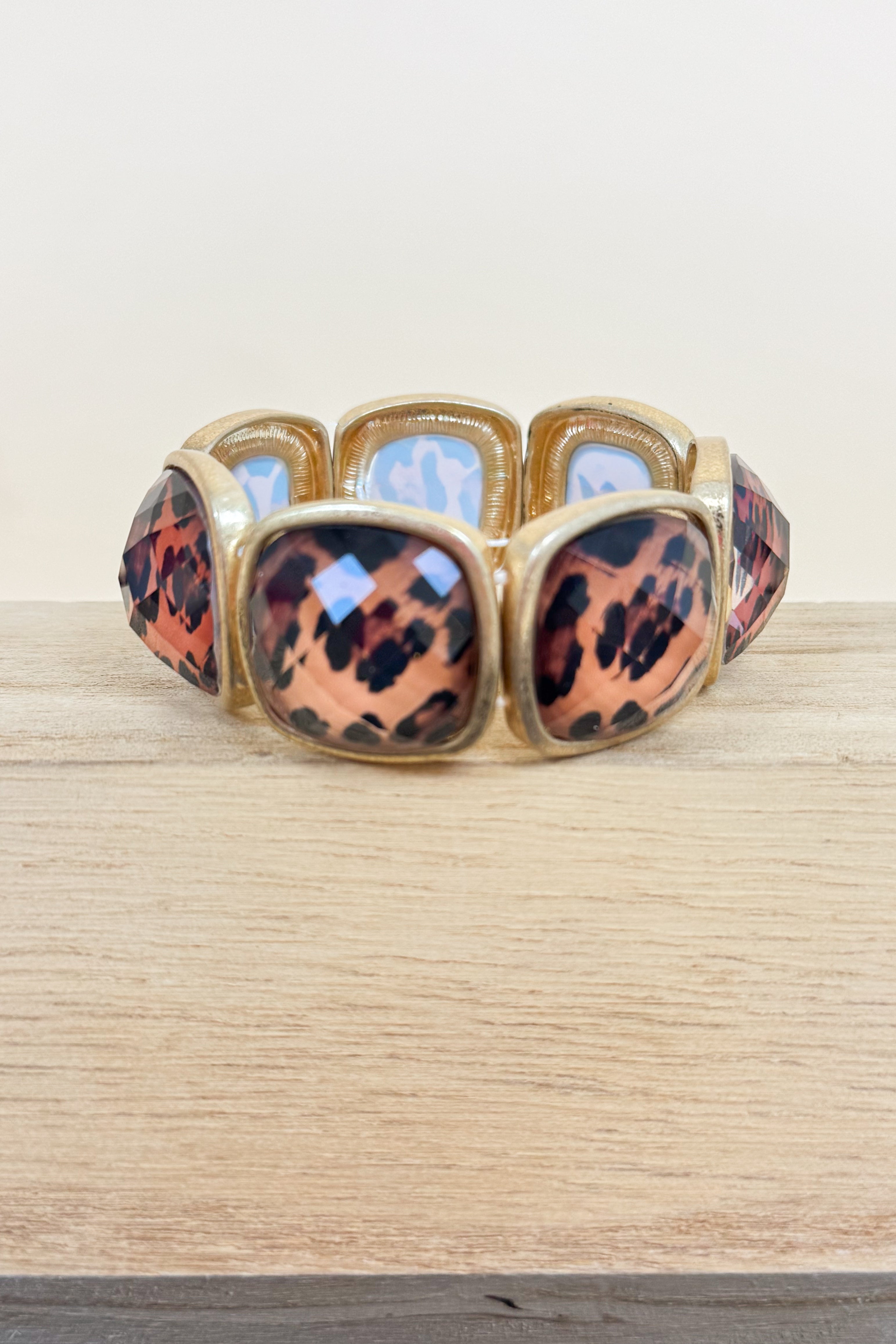 Bracelet with leopard print and gold accents on a wooden surface