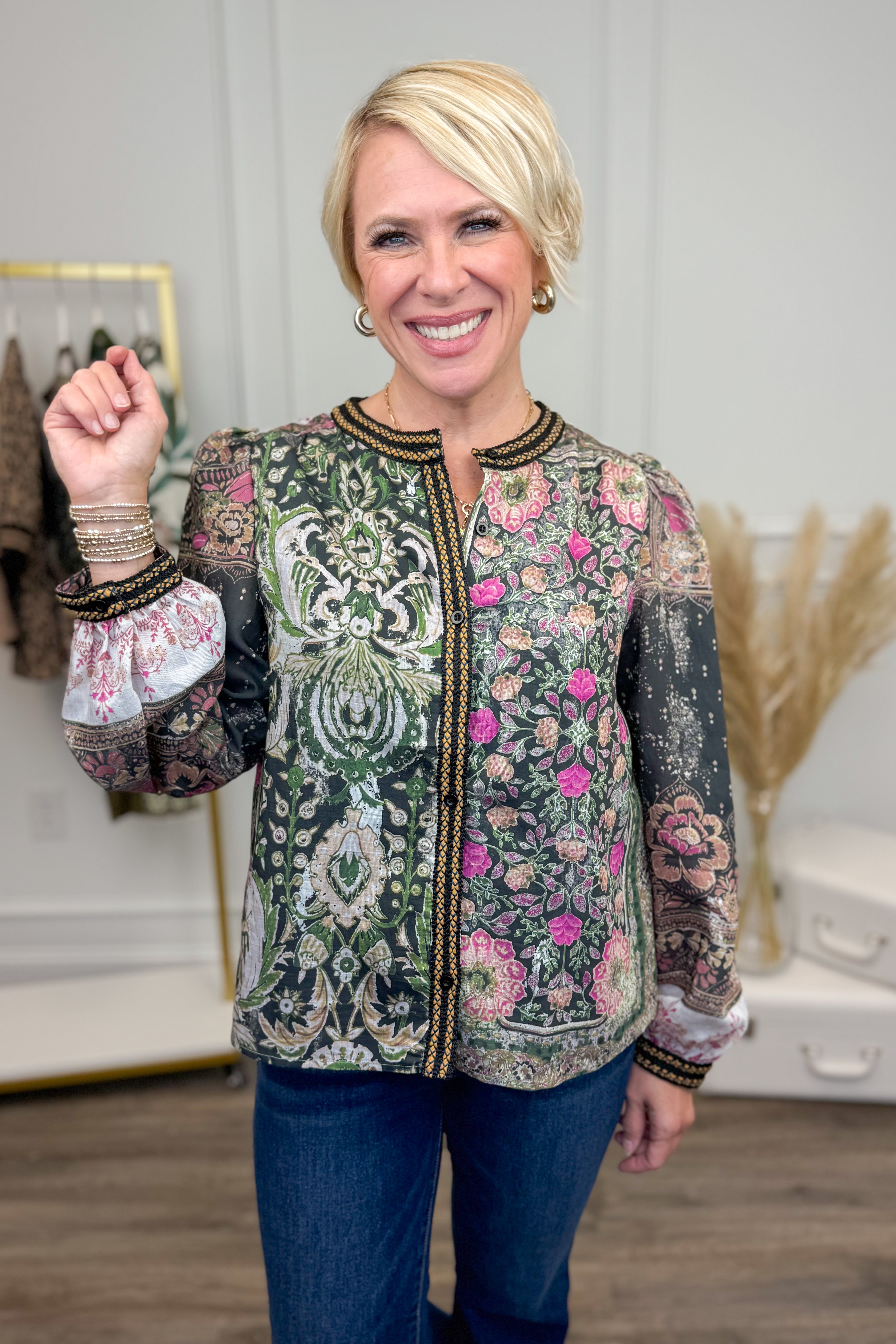 Woman wearing a patterned shirt with floral and paisley designs indoors.