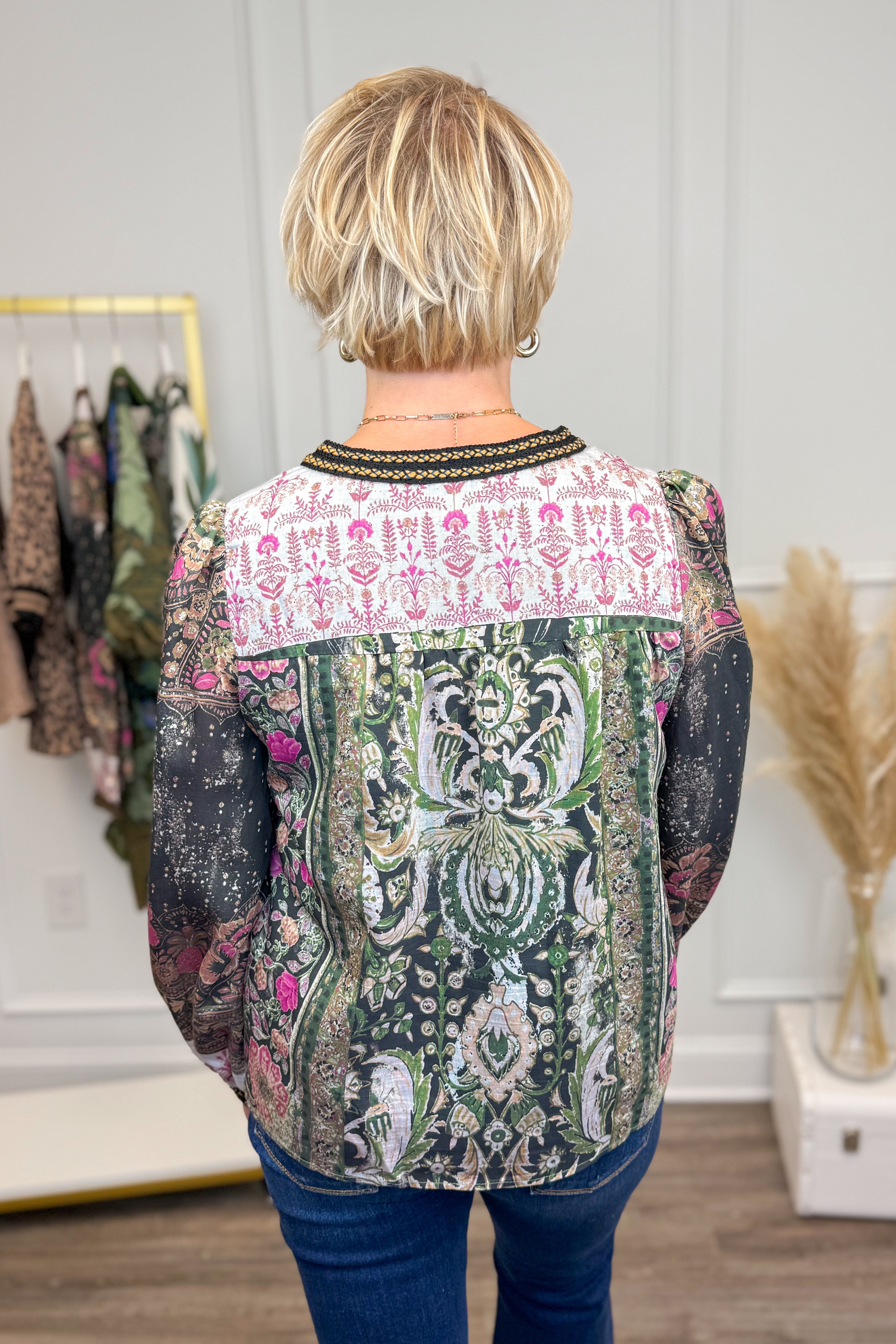 Person wearing a patterned top in a clothing store setting