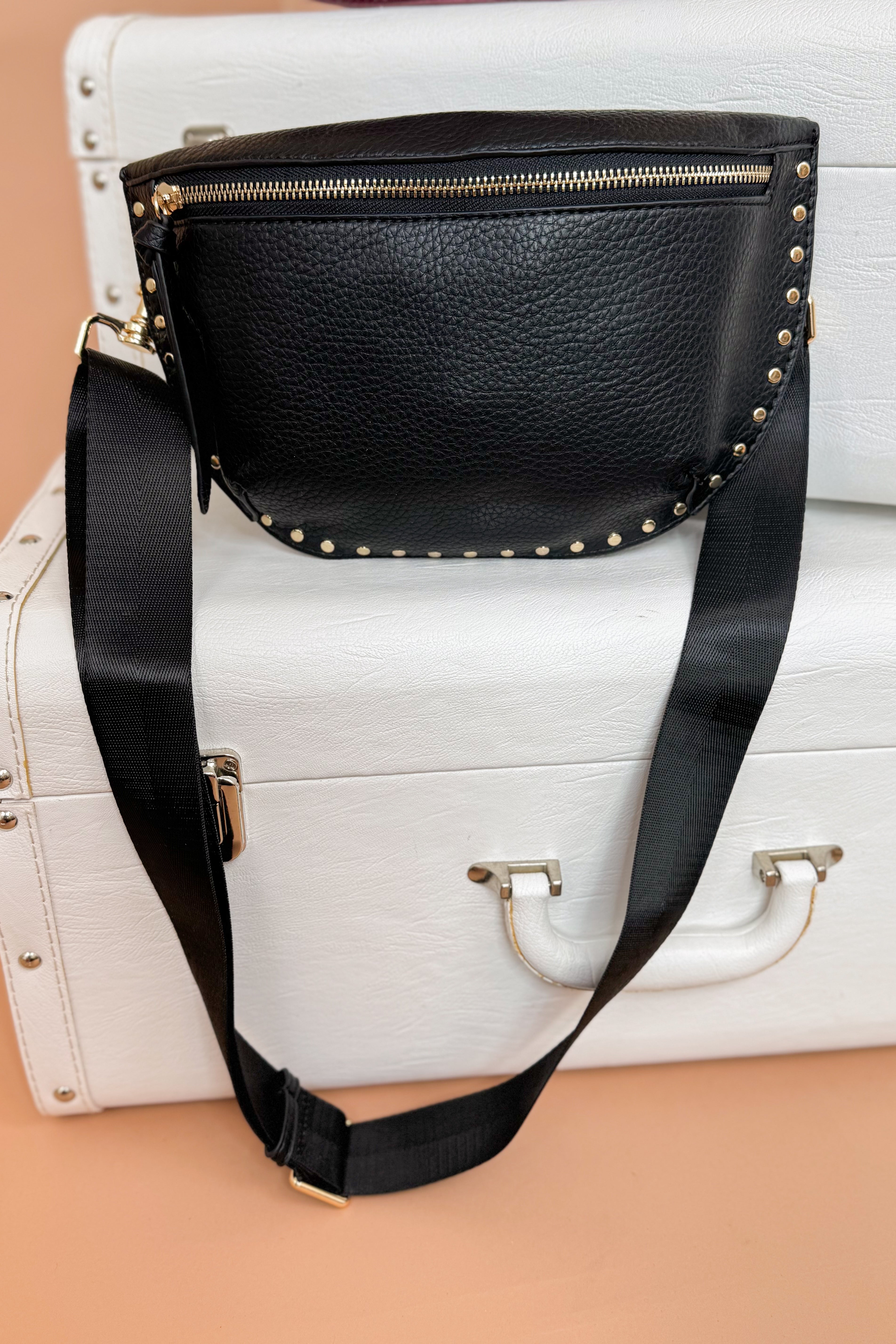 Black handbag with gold studs on a white suitcase