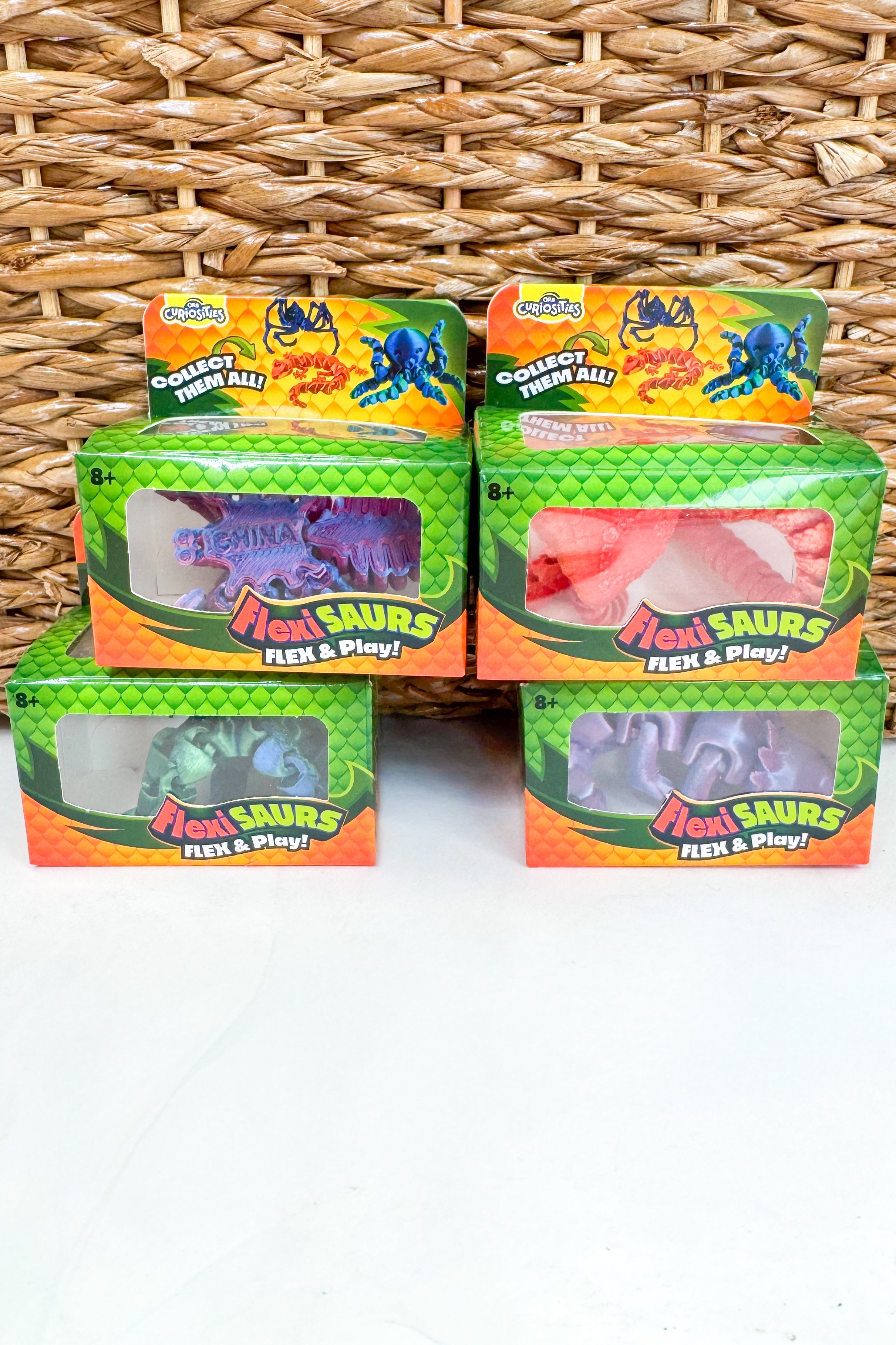 Five boxes of Flex & Play toy figures on a wicker surface