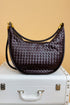 Brown woven handbag on a white suitcase with a beige background