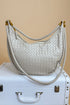 White woven handbag with gold accents on a beige background