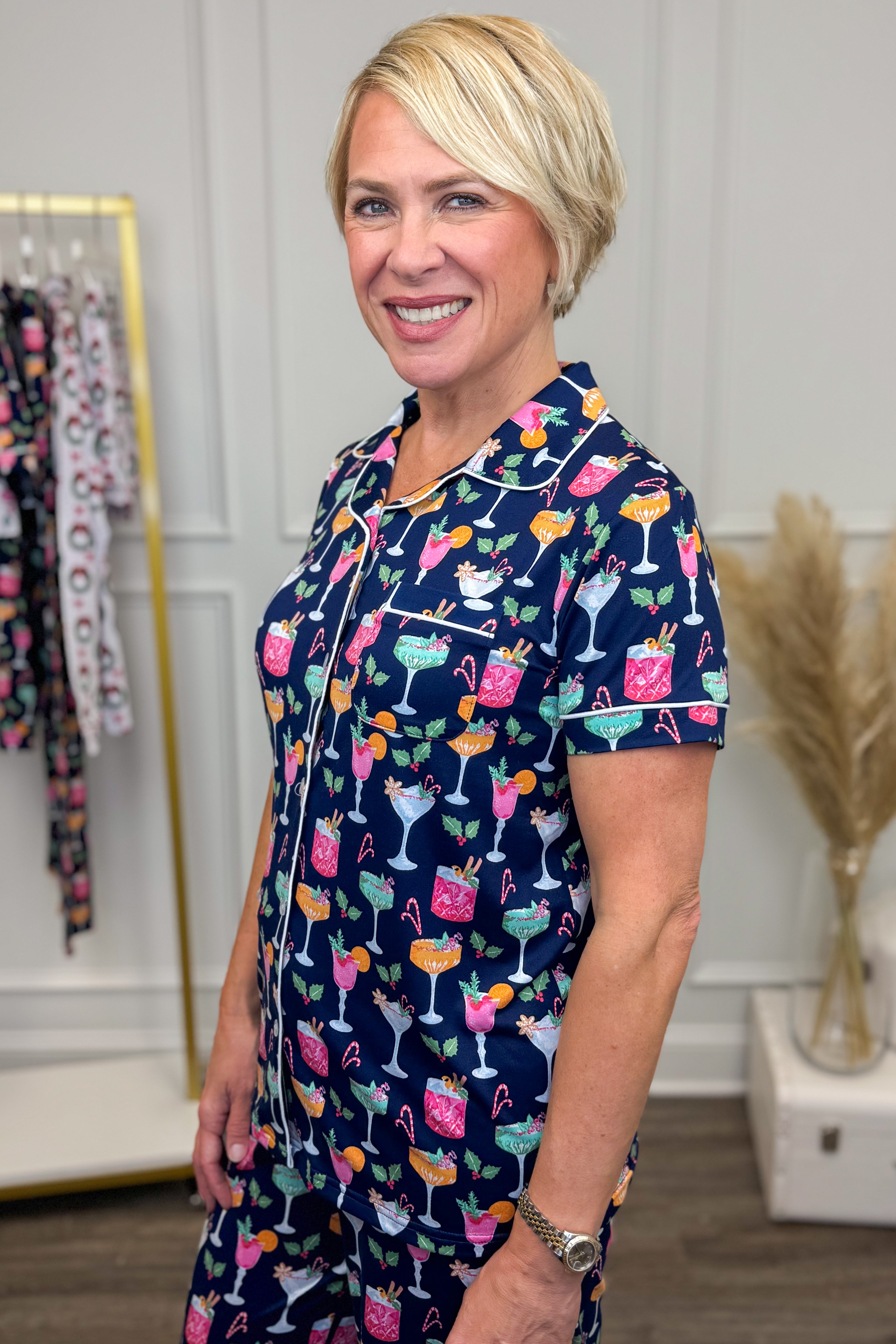 Woman wearing a navy blue dress with colorful cocktail print in a room setting.