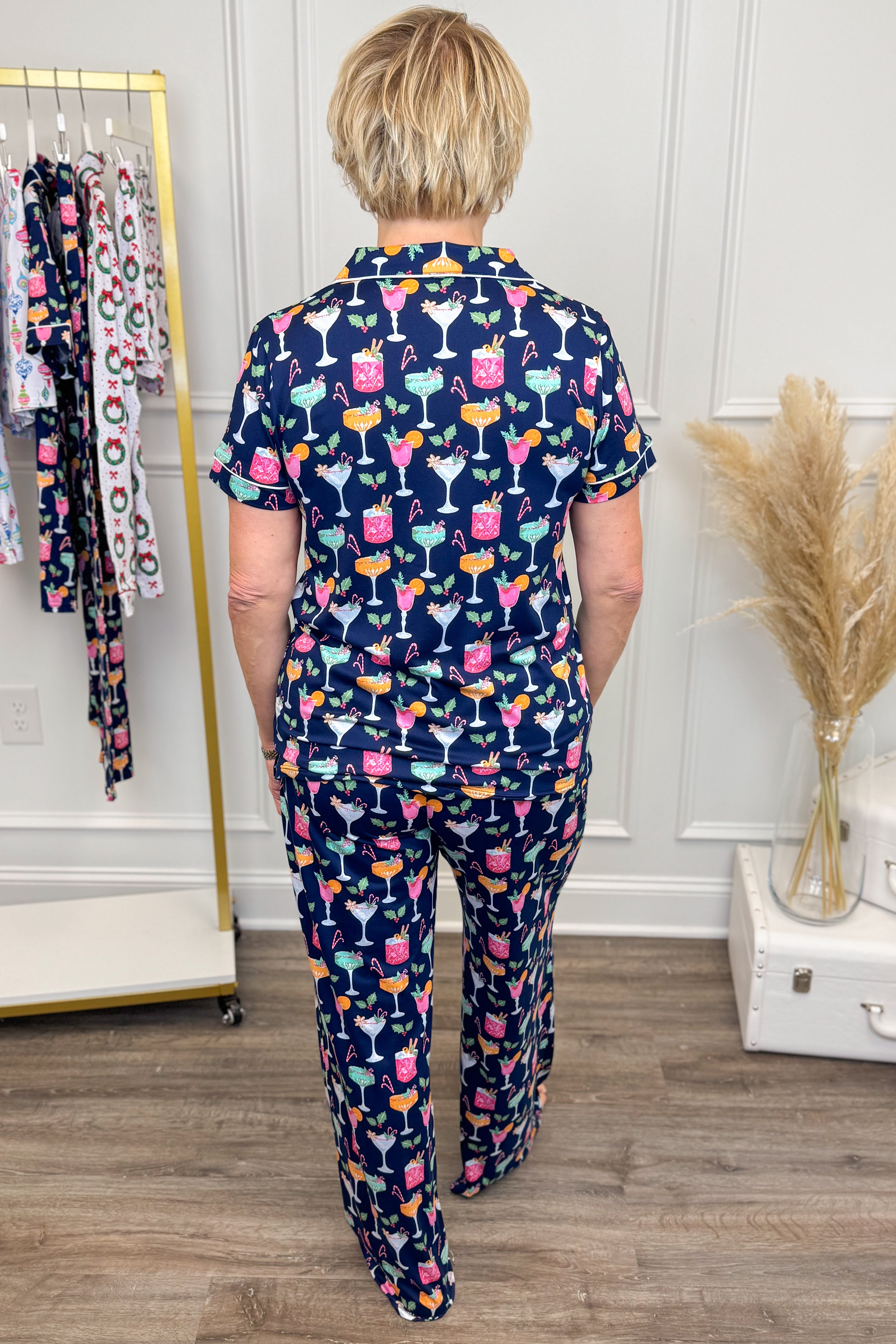 Person wearing a navy pajama set with colorful drink patterns in a room.