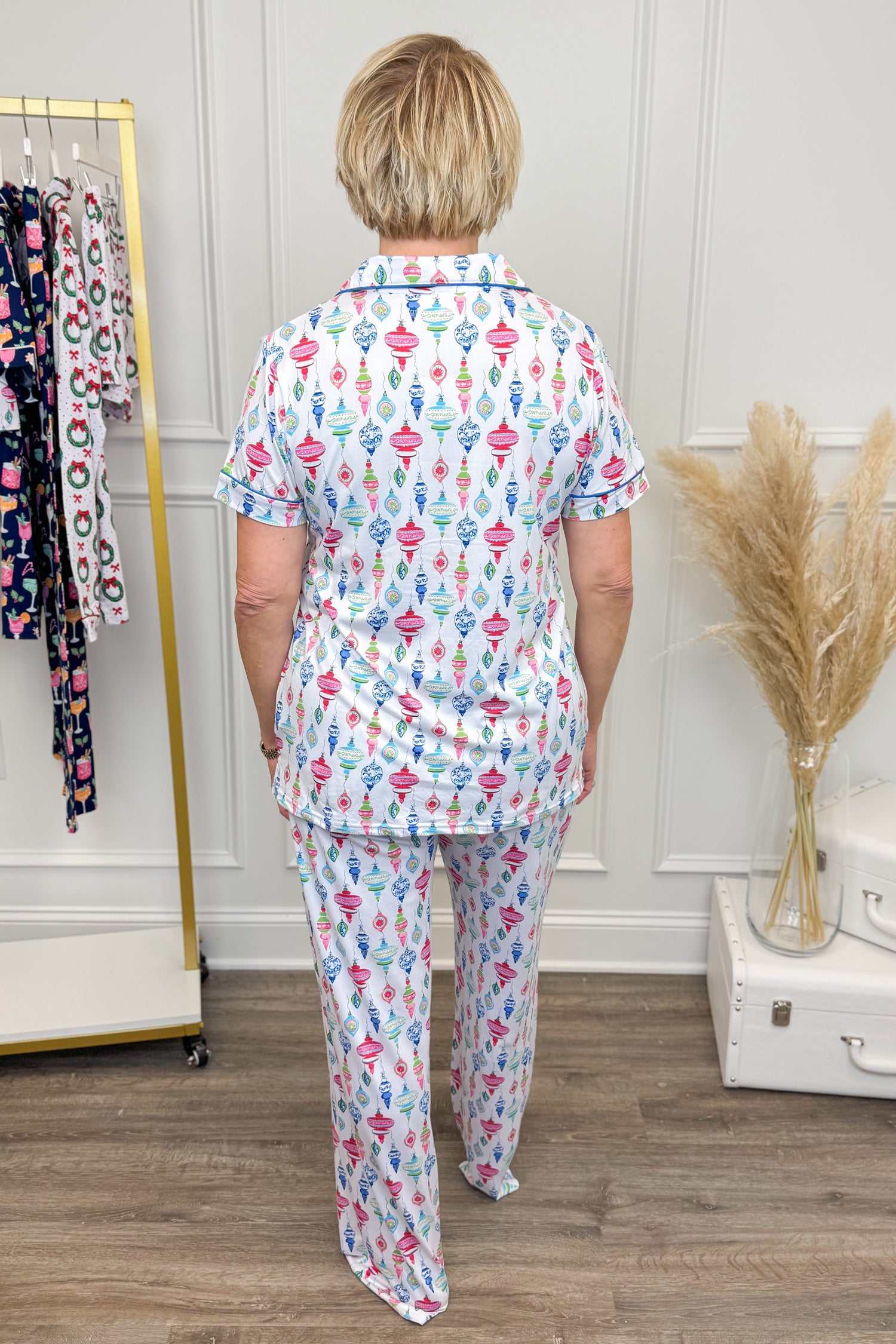 Person wearing a colorful pajama set in a room with a rack of clothes and decorative items.