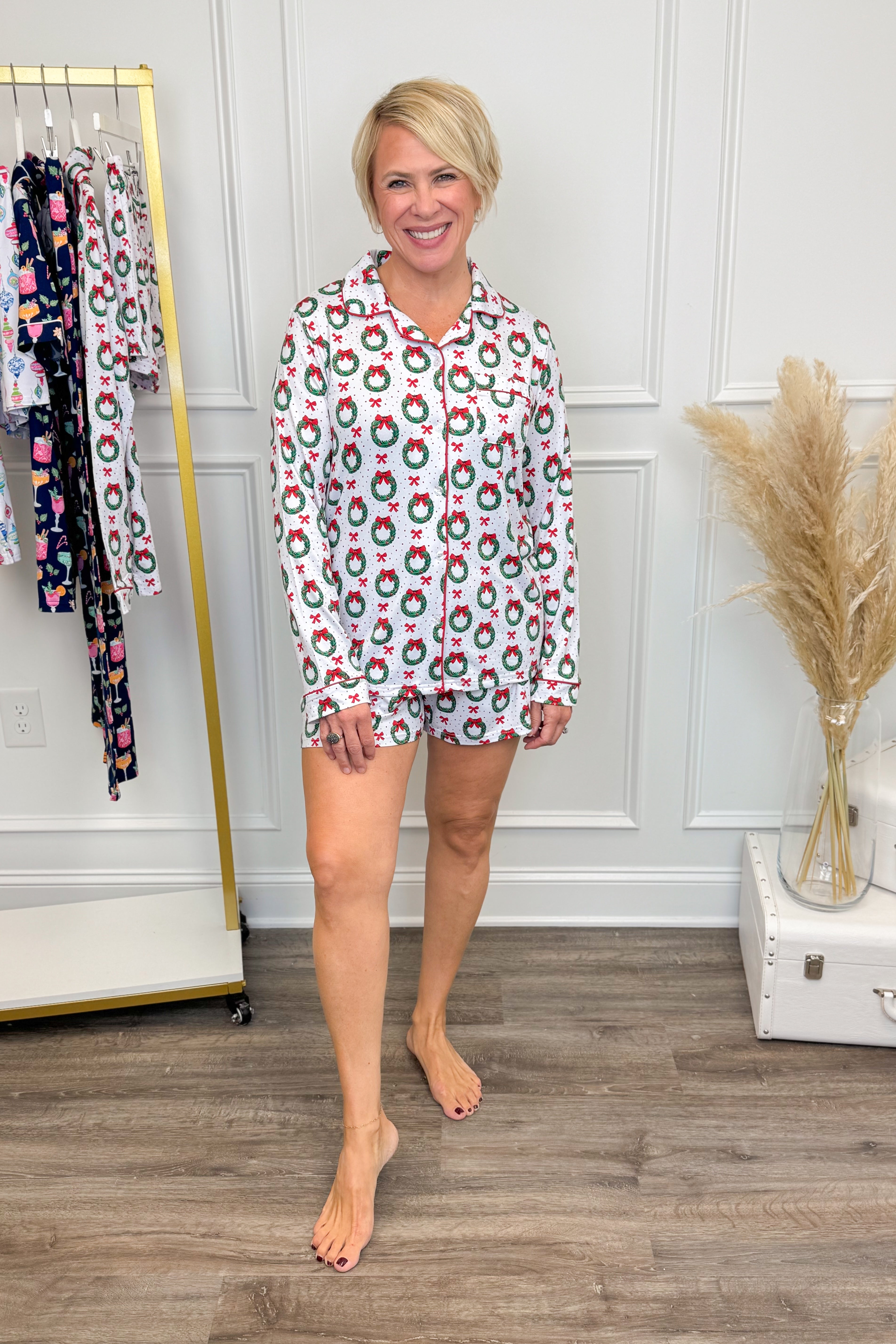 Woman wearing a patterned pajama set in a room with a rack of clothes and decorative elements.