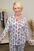 Woman wearing a patterned pajama set in a room with a rack of clothes and decorative elements.
