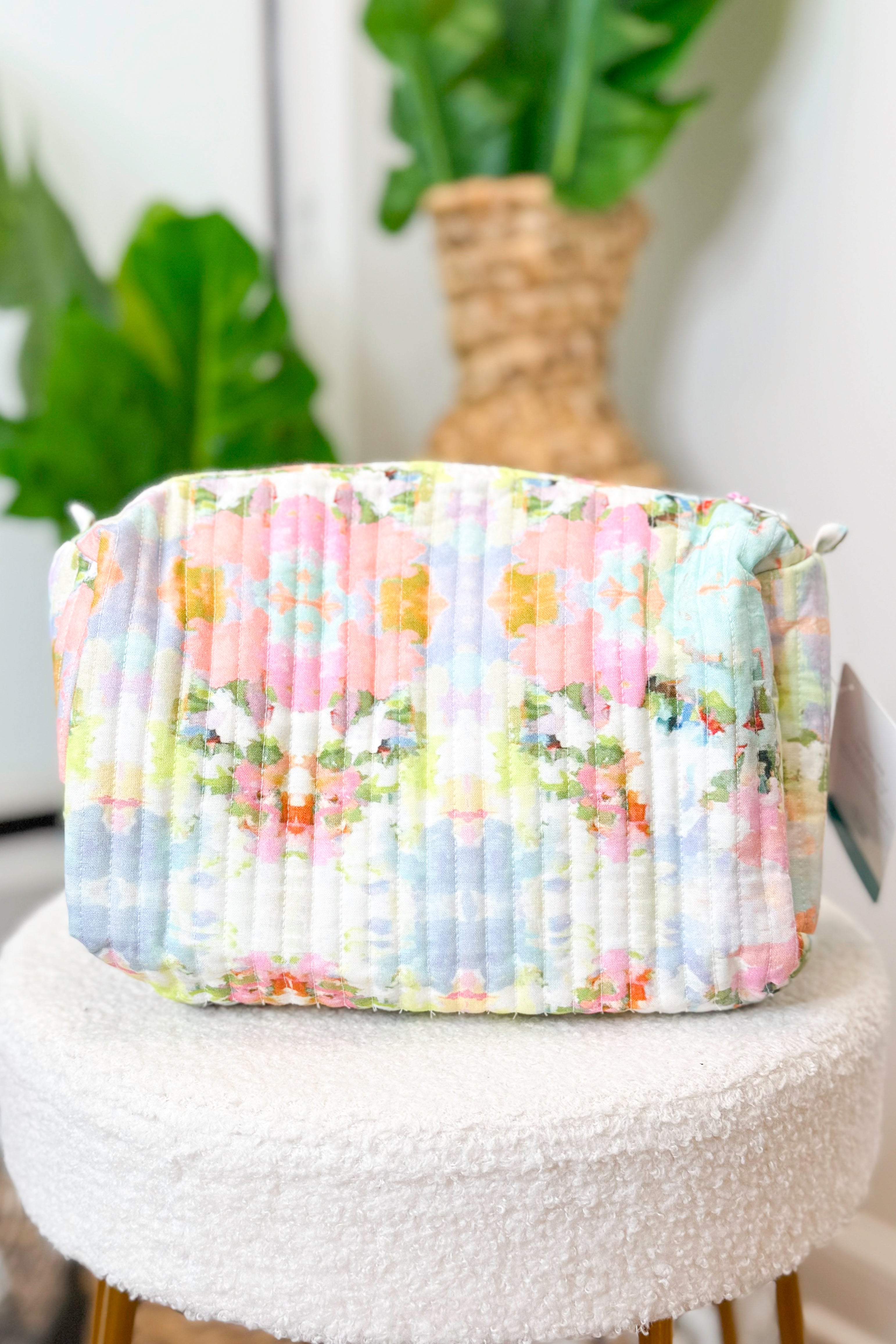 Floral-patterned fabric basket on a white surface with plants in the background