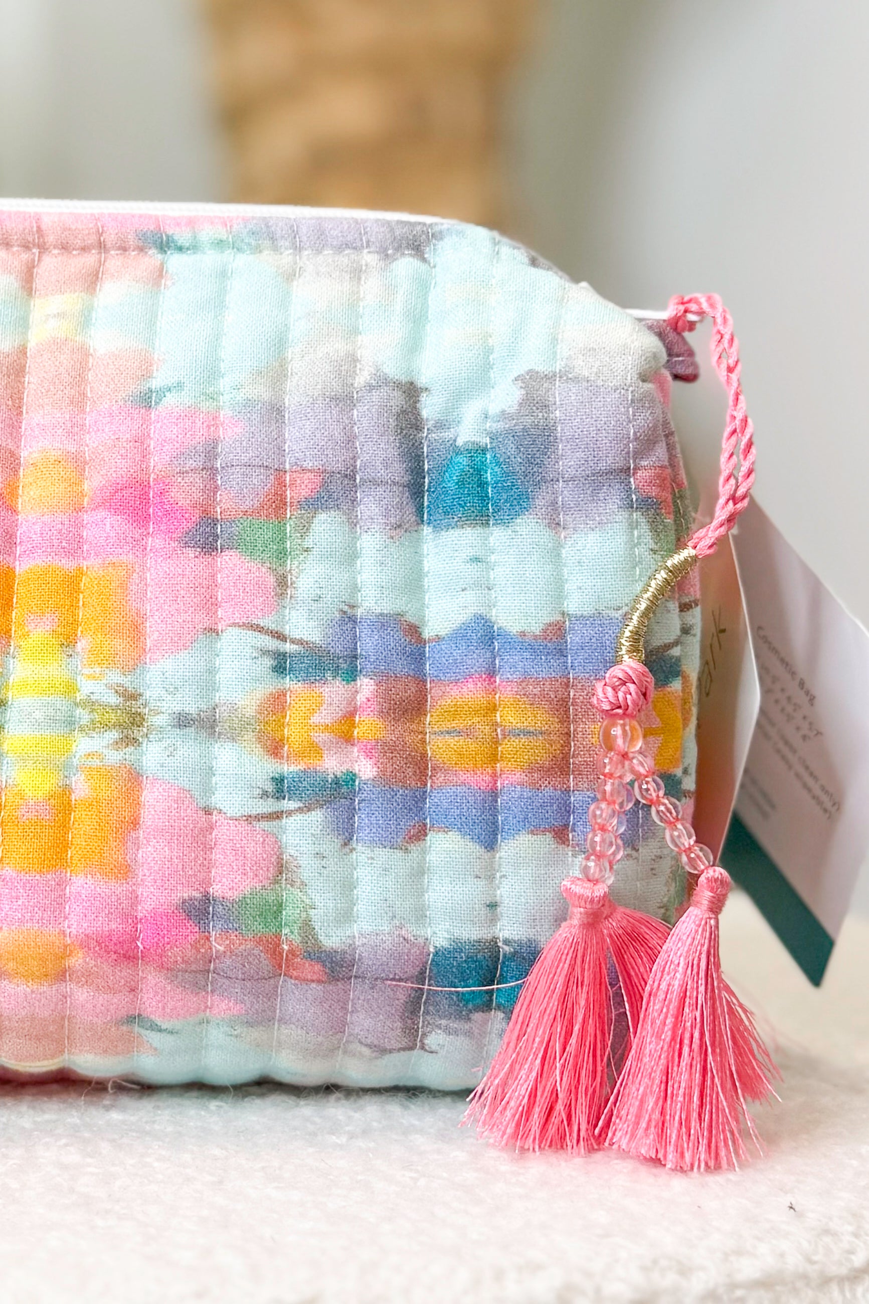 Colorful textured pouch with pink tassels on a light background