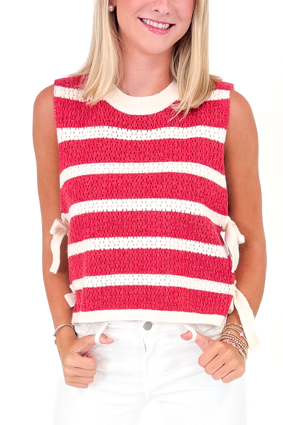 Woman wearing a red and white striped sleeveless top with bow details.