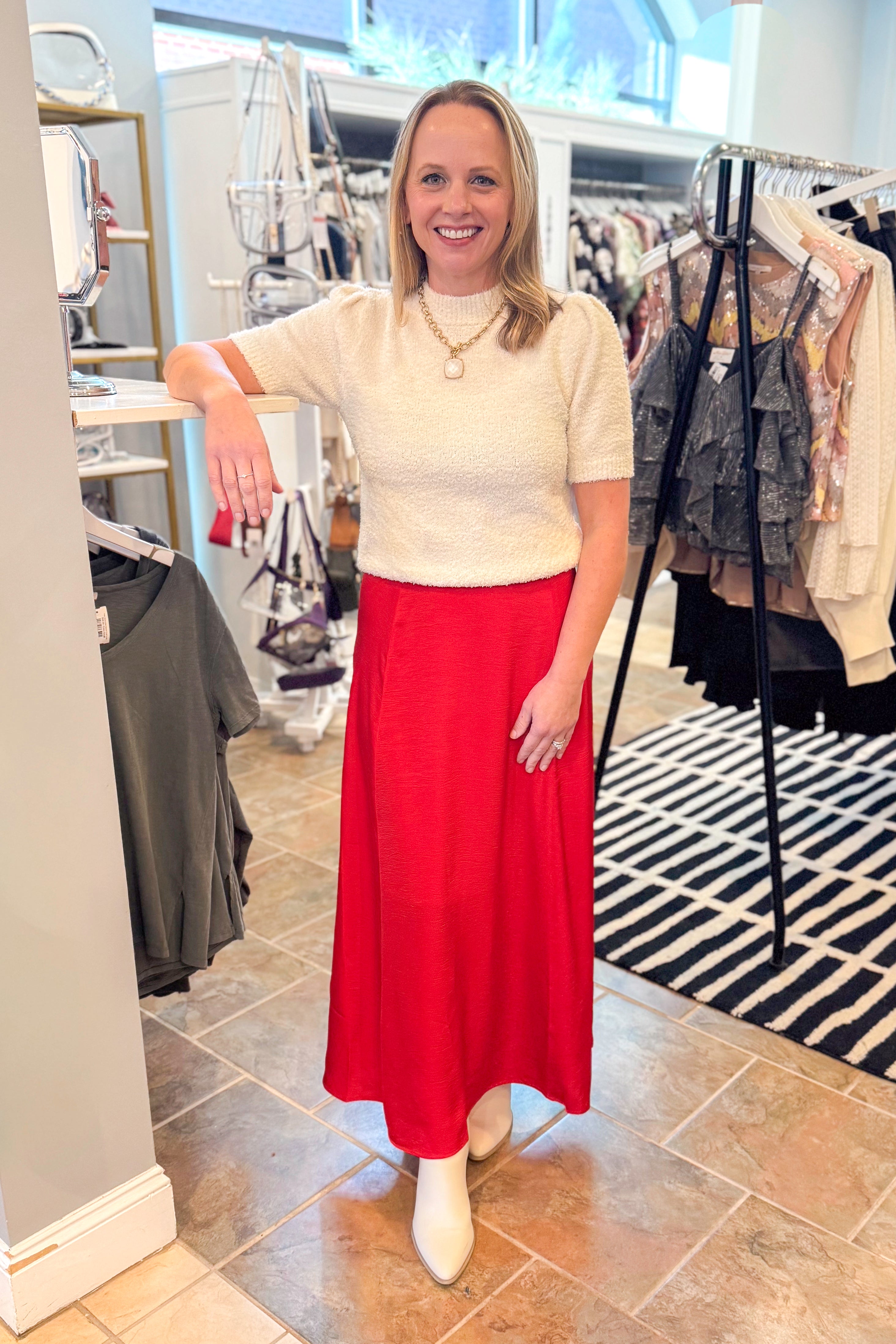 Front view of woman wearing cream top with Festive Red Northpointe Midi Skirt at a boutique.