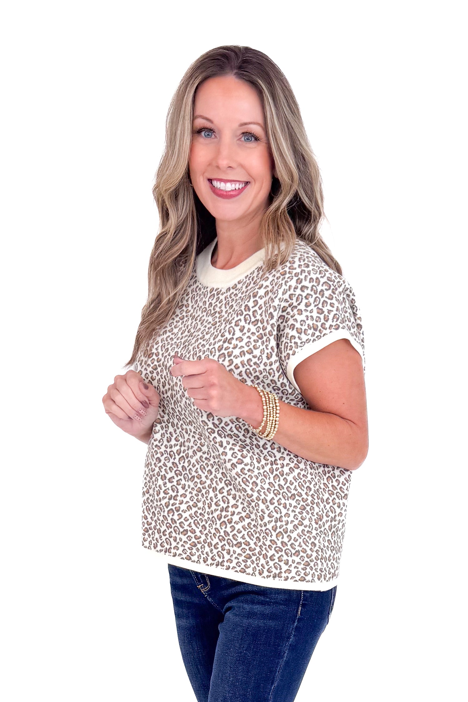 Woman wearing a leopard print top and dark jeans on a white background