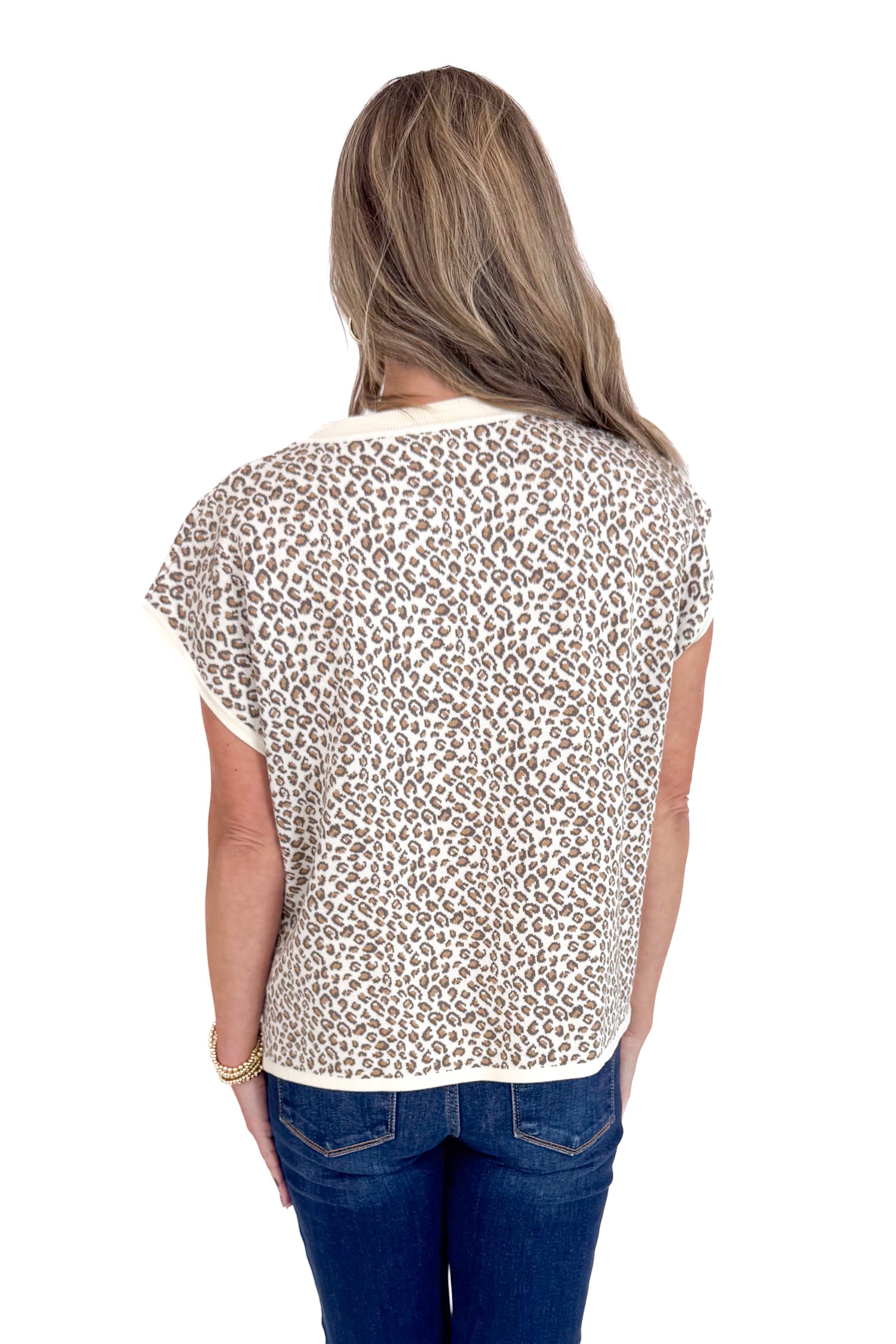 Woman wearing a leopard print top and blue jeans on a white background