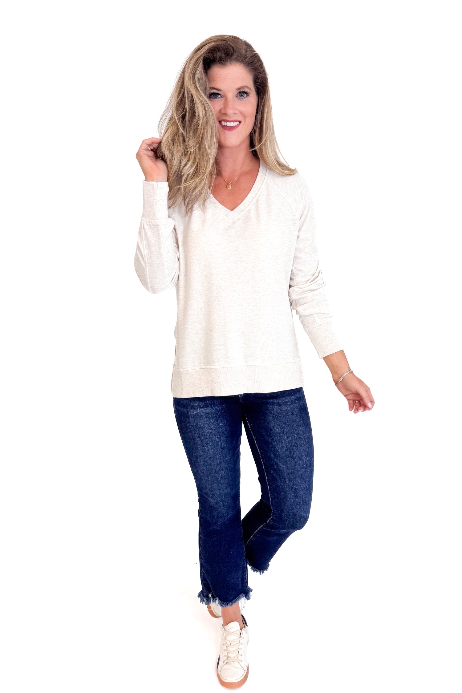 Woman wearing a white long-sleeve top and blue jeans on a white background