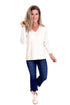 Woman wearing a white long-sleeve top and blue jeans on a white background