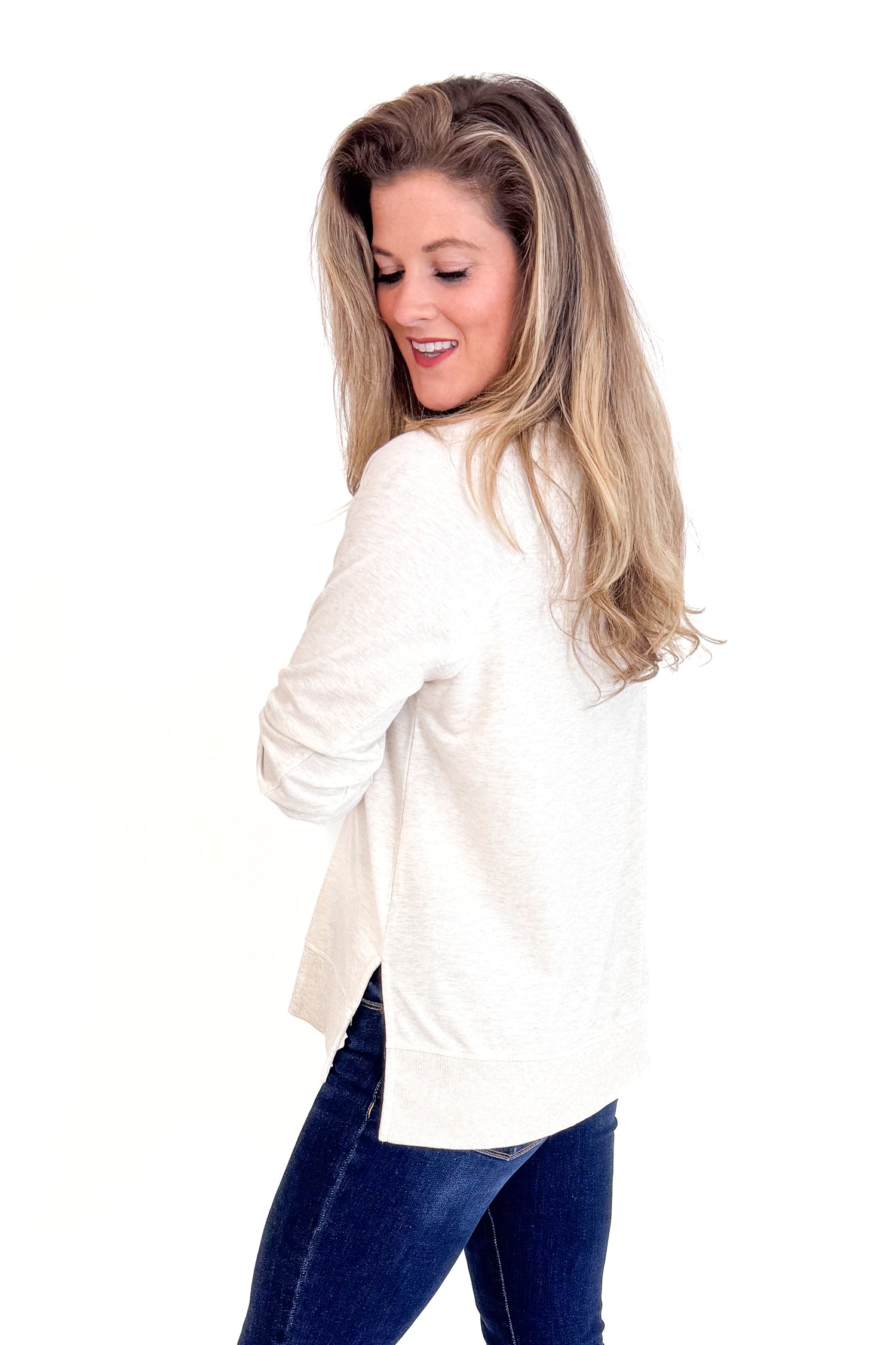 Woman wearing a white blazer and blue jeans on a white background