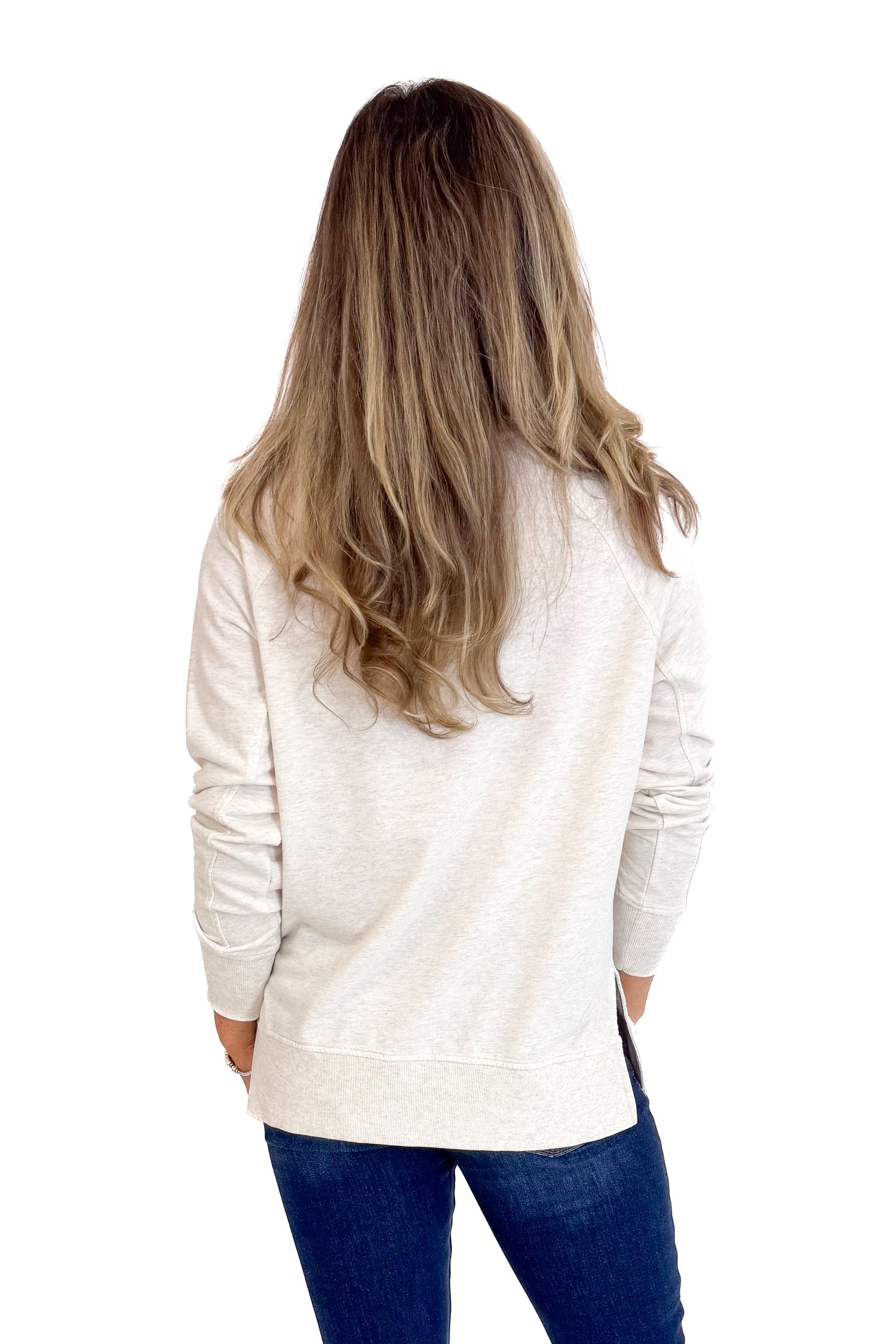 Person wearing a white sweater and blue jeans from behind on a white background