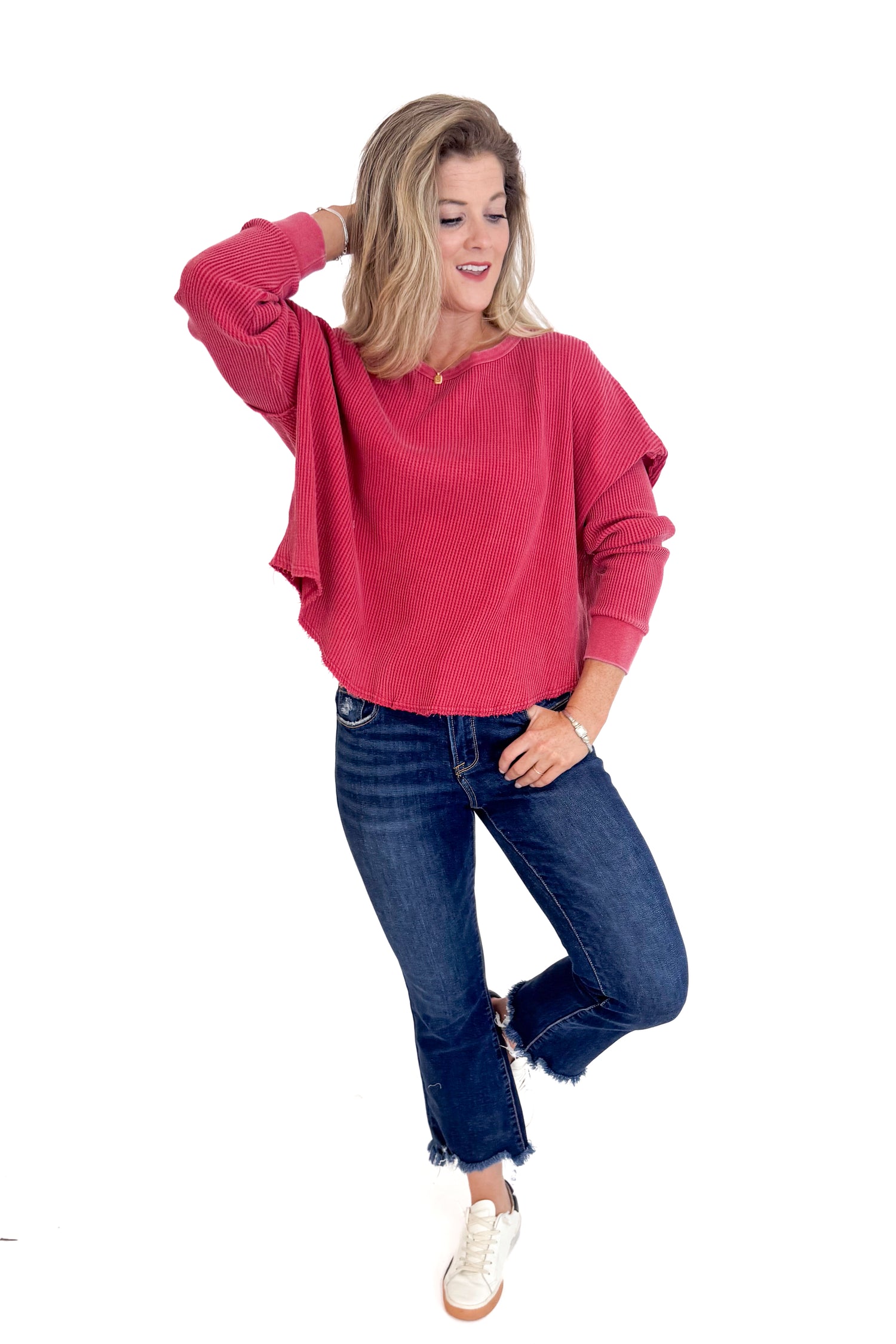 Woman wearing a red sweater and blue jeans on a white background