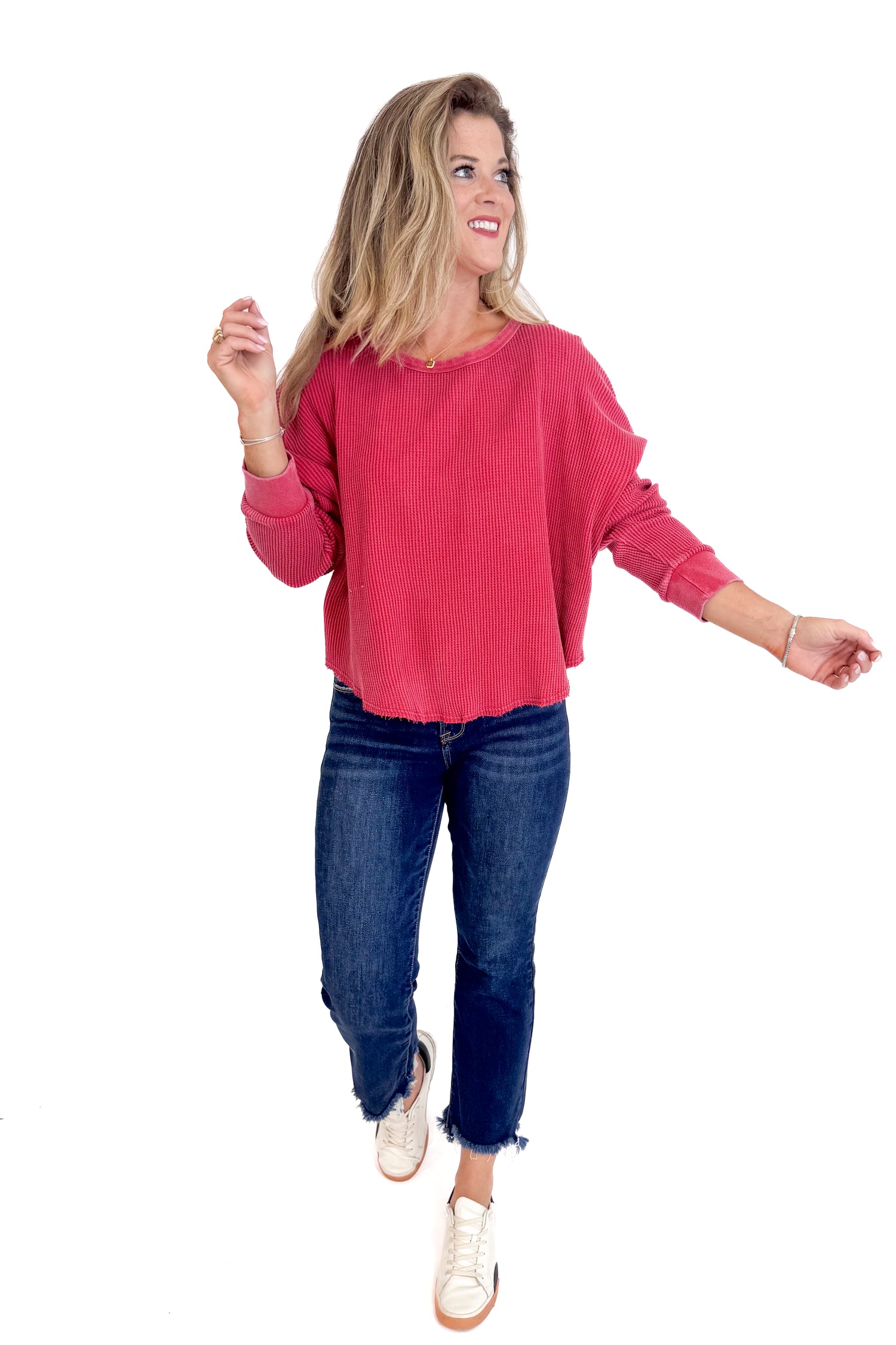 Woman wearing a red sweater and blue jeans on a white background