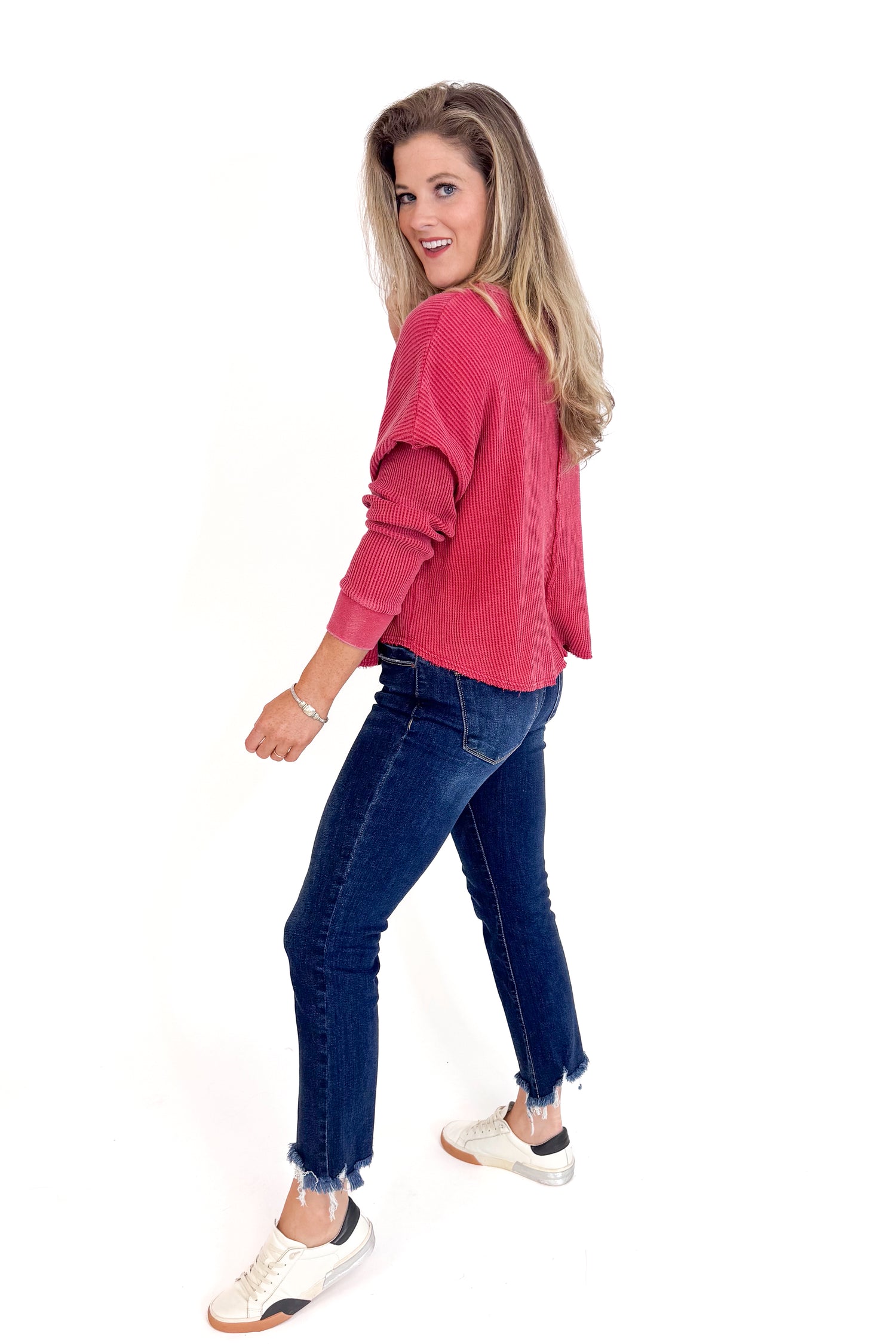 Woman wearing a red sweater and blue jeans on a white background