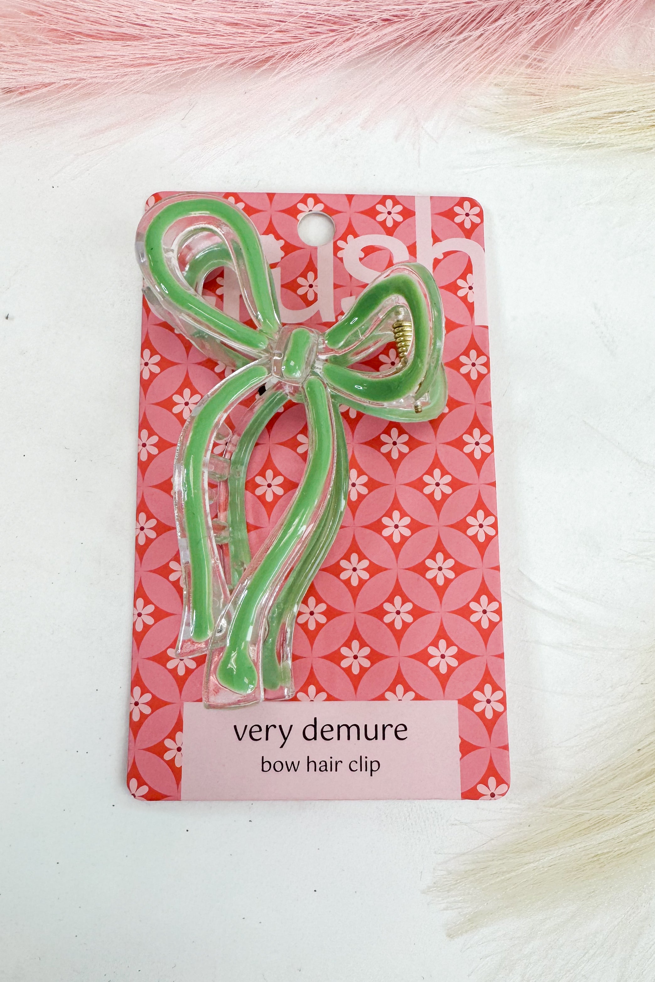 Green bow hair clip on a pink floral patterned card with &