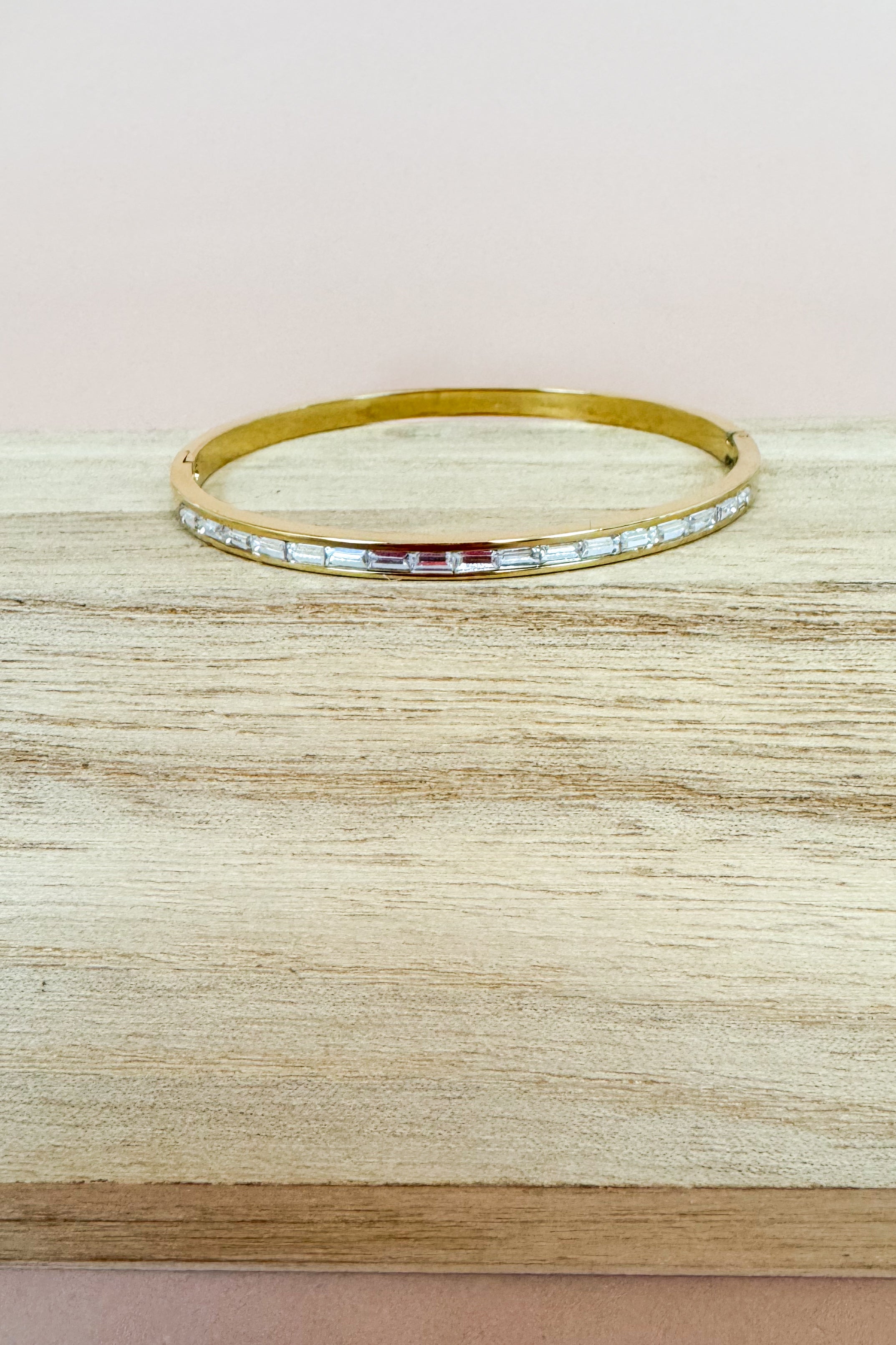 Gold bracelet with small stones on a beige surface