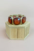 Ring with amber stones on a wooden stand against a beige background