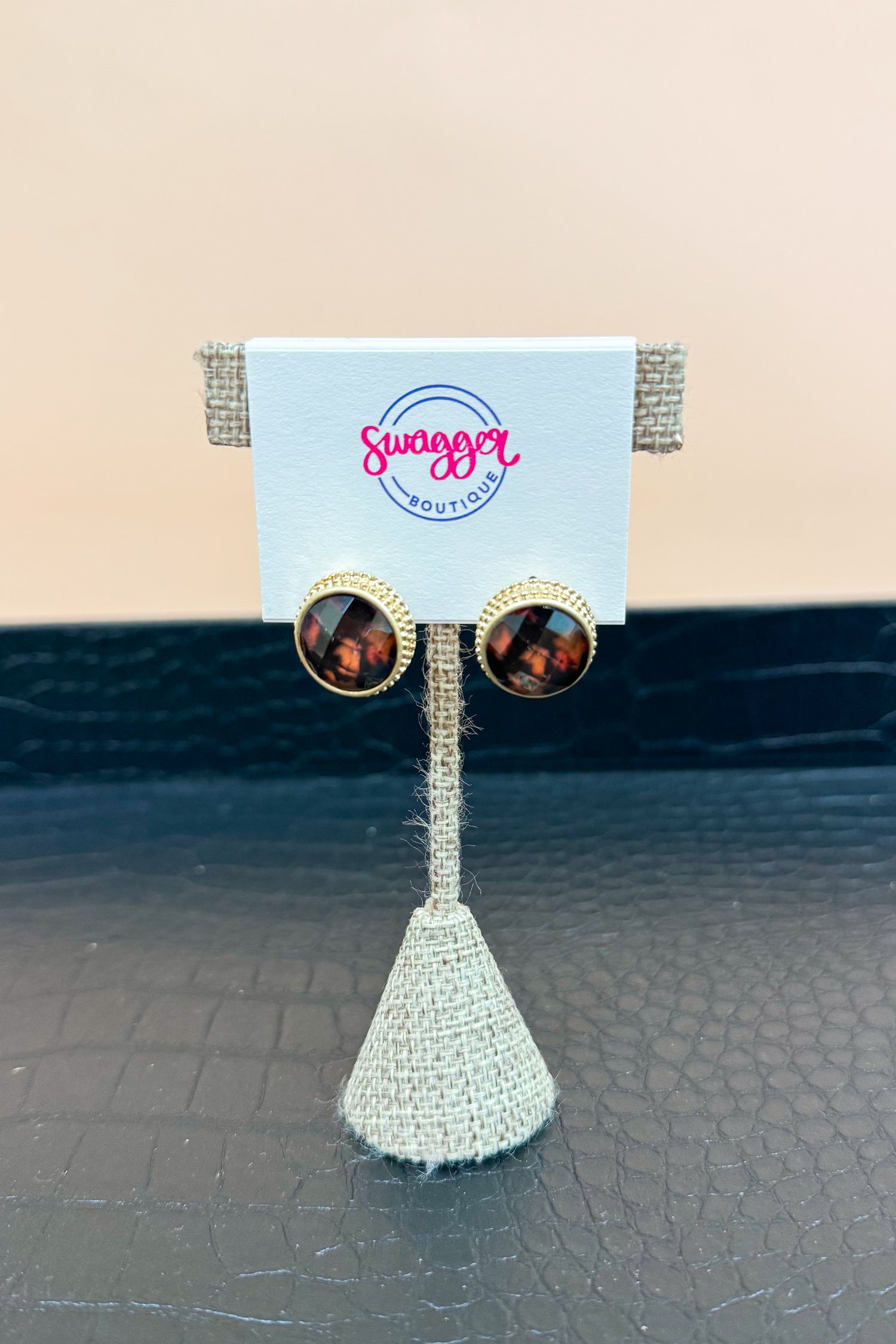 Earrings on a Swagger Boutique card against a textured surface