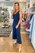Woman in a blue jumpsuit standing in a clothing store.