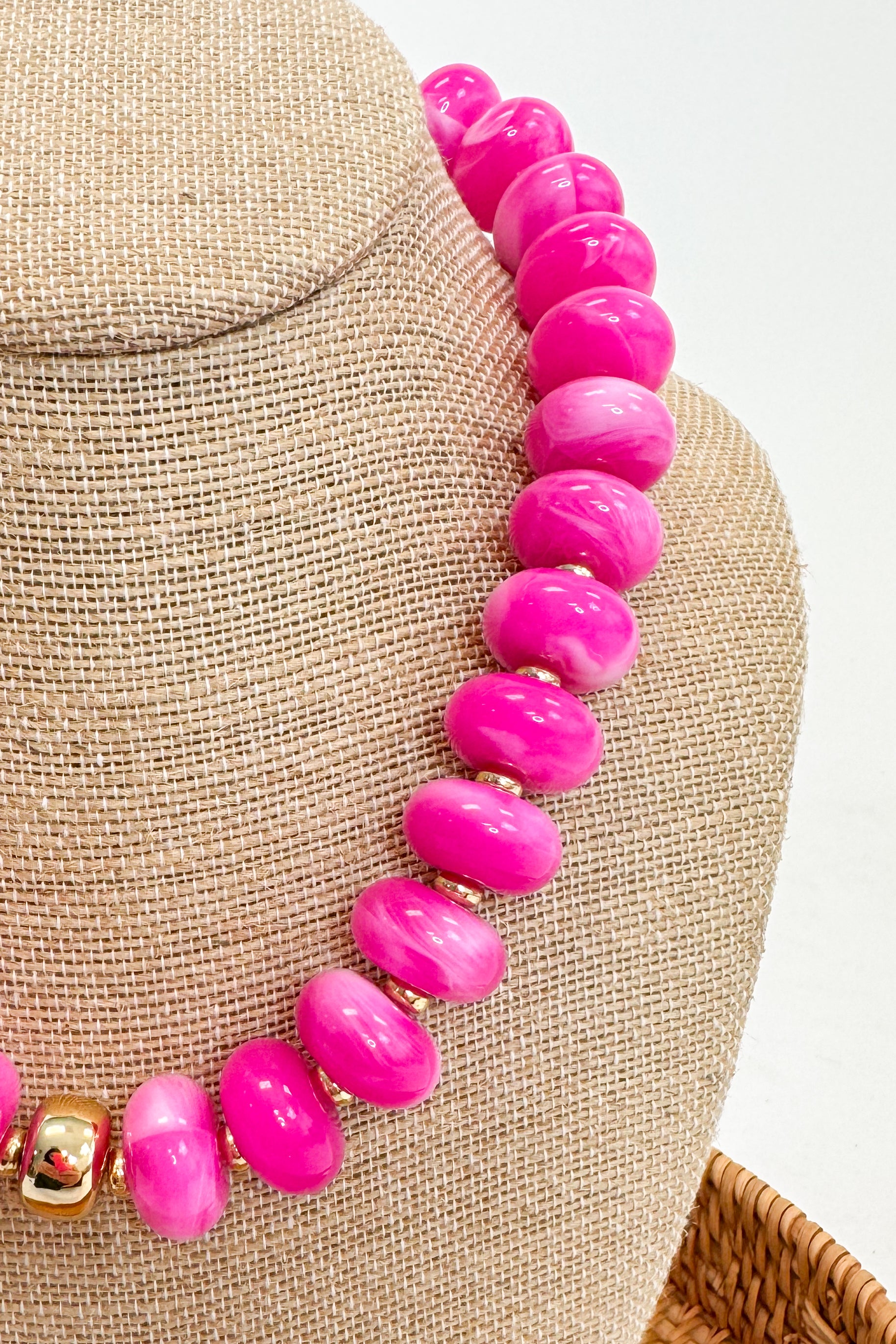 Necklace with pink beads on a mannequin bust against a neutral background