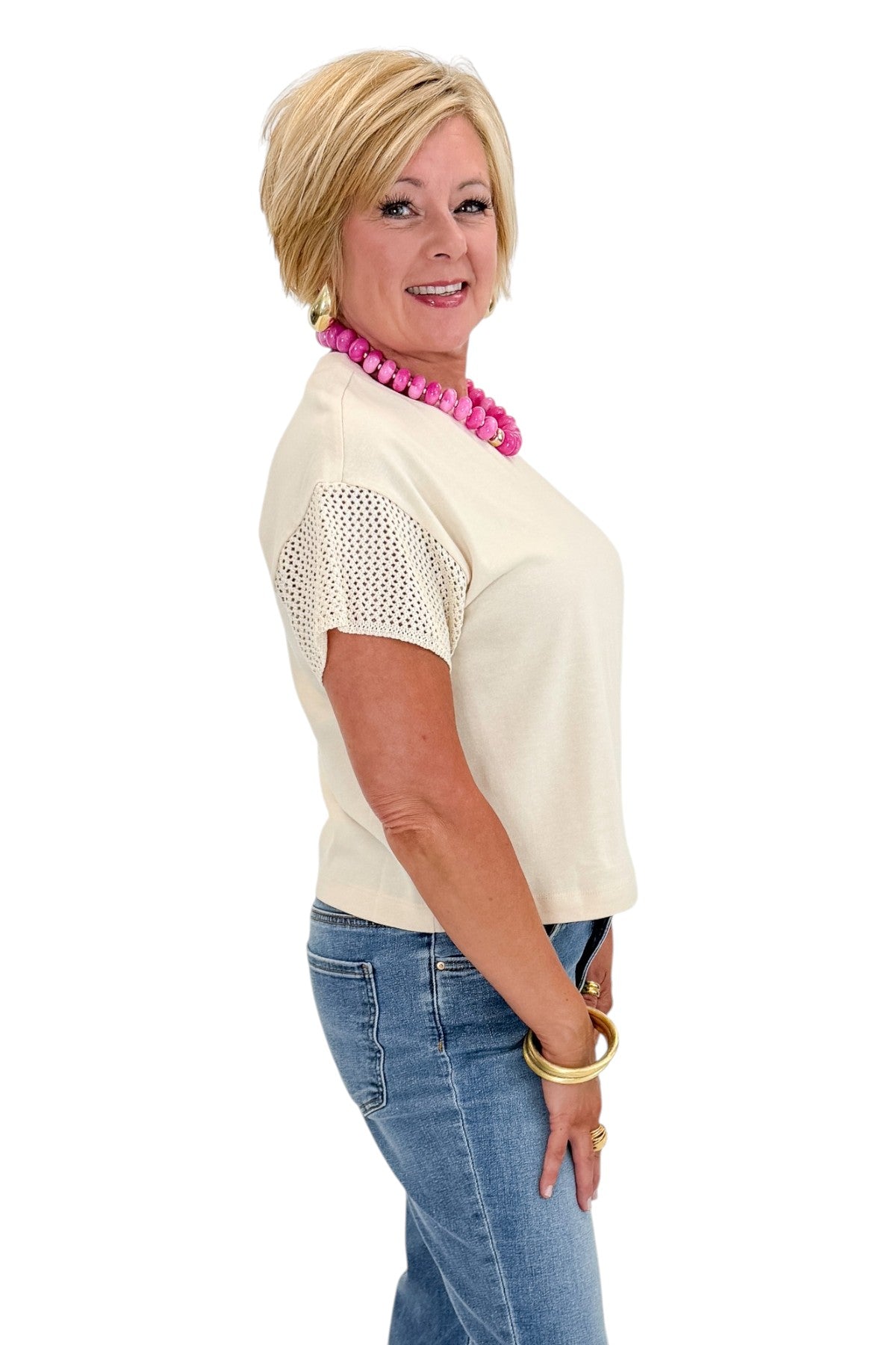 Side view of woman wearing Swagger Boutiqueās Island Coconut Banyan Top by Z Supply with jeans against white studio background.