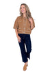 Front view of woman wearing camel stitch detail sweater with jeans against white studio background.
