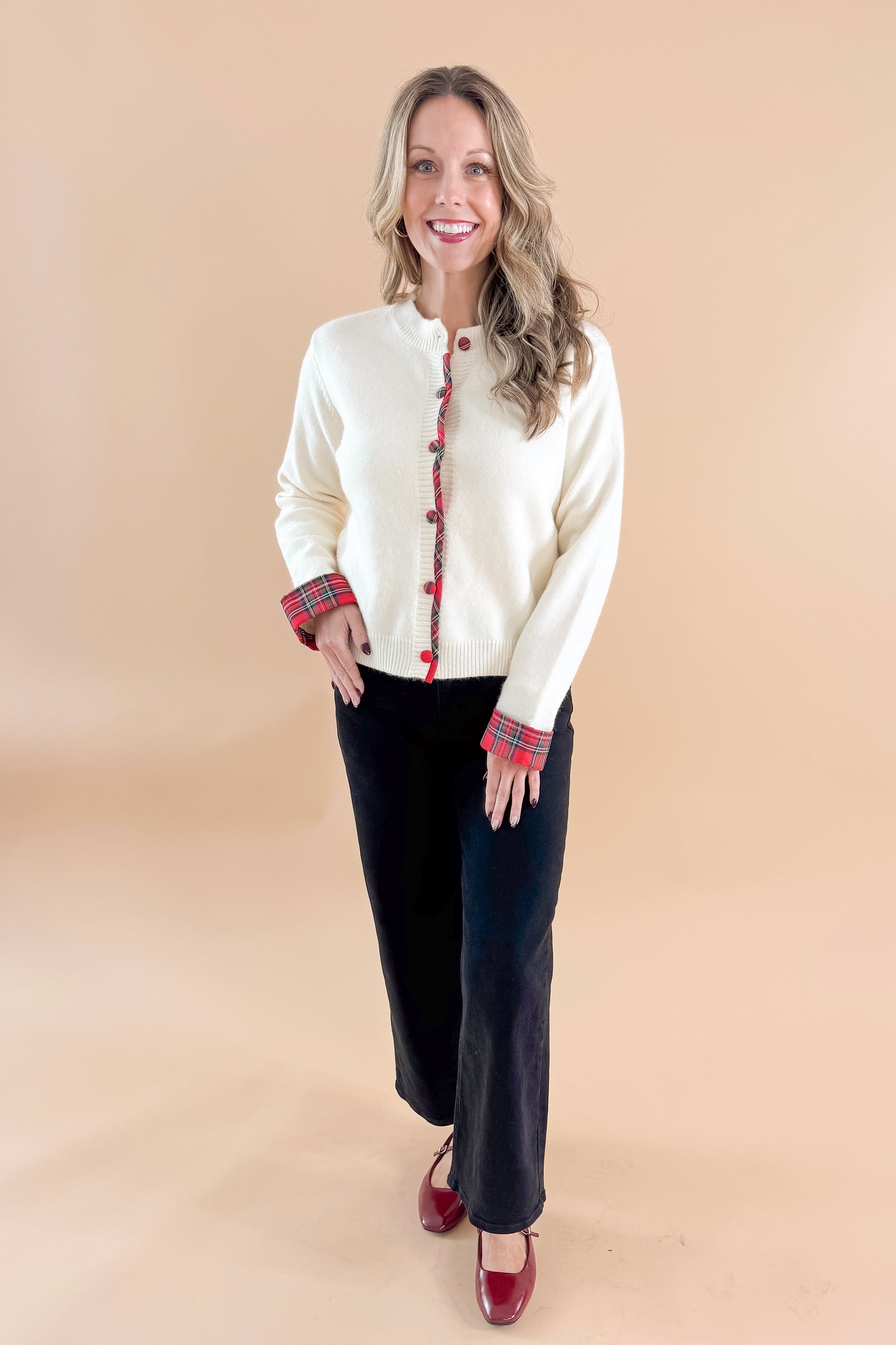 Front view of woman wearing Cream With Tartan Detail Button Up Cardigan with jeans against tan studio background.