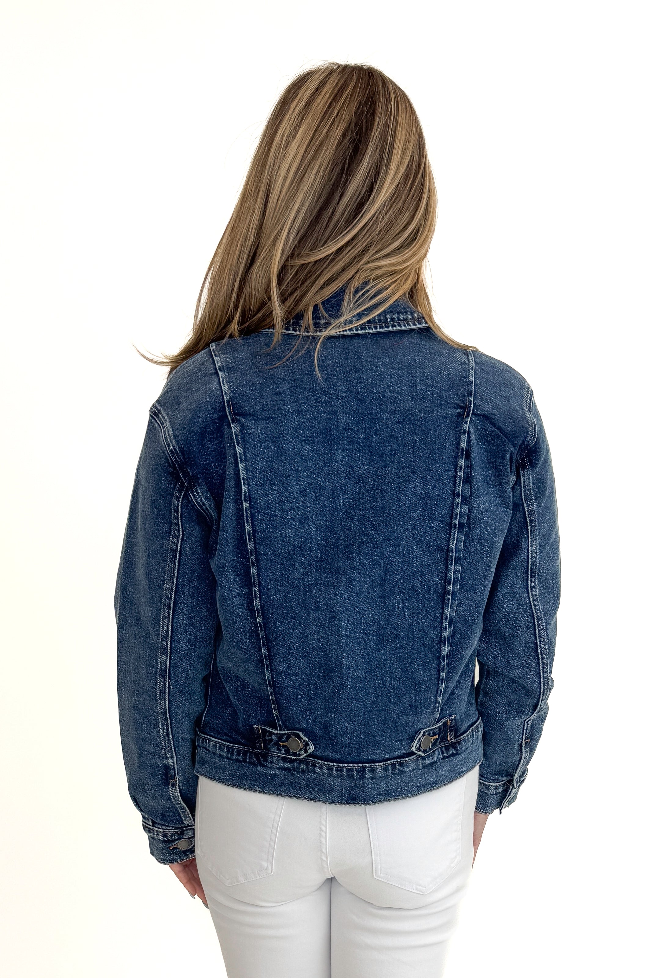 Back view of woman wearing Dark Wash Denim Jacket with jeans against white studio background.