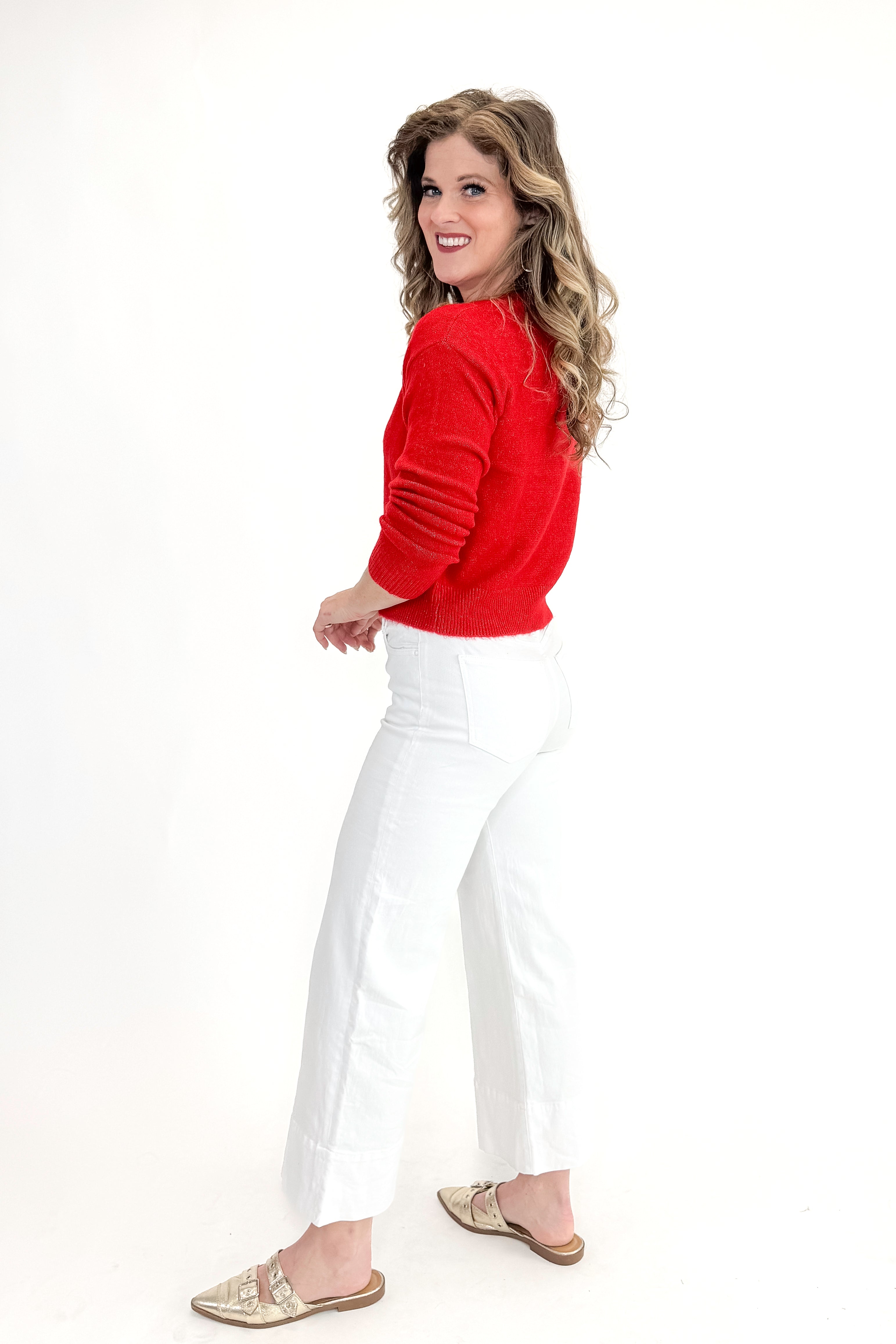 Side view of woman wearing top with Meg Optic White Pintuck Wide Leg Jeans by Kut from the Kloth against white studio background.