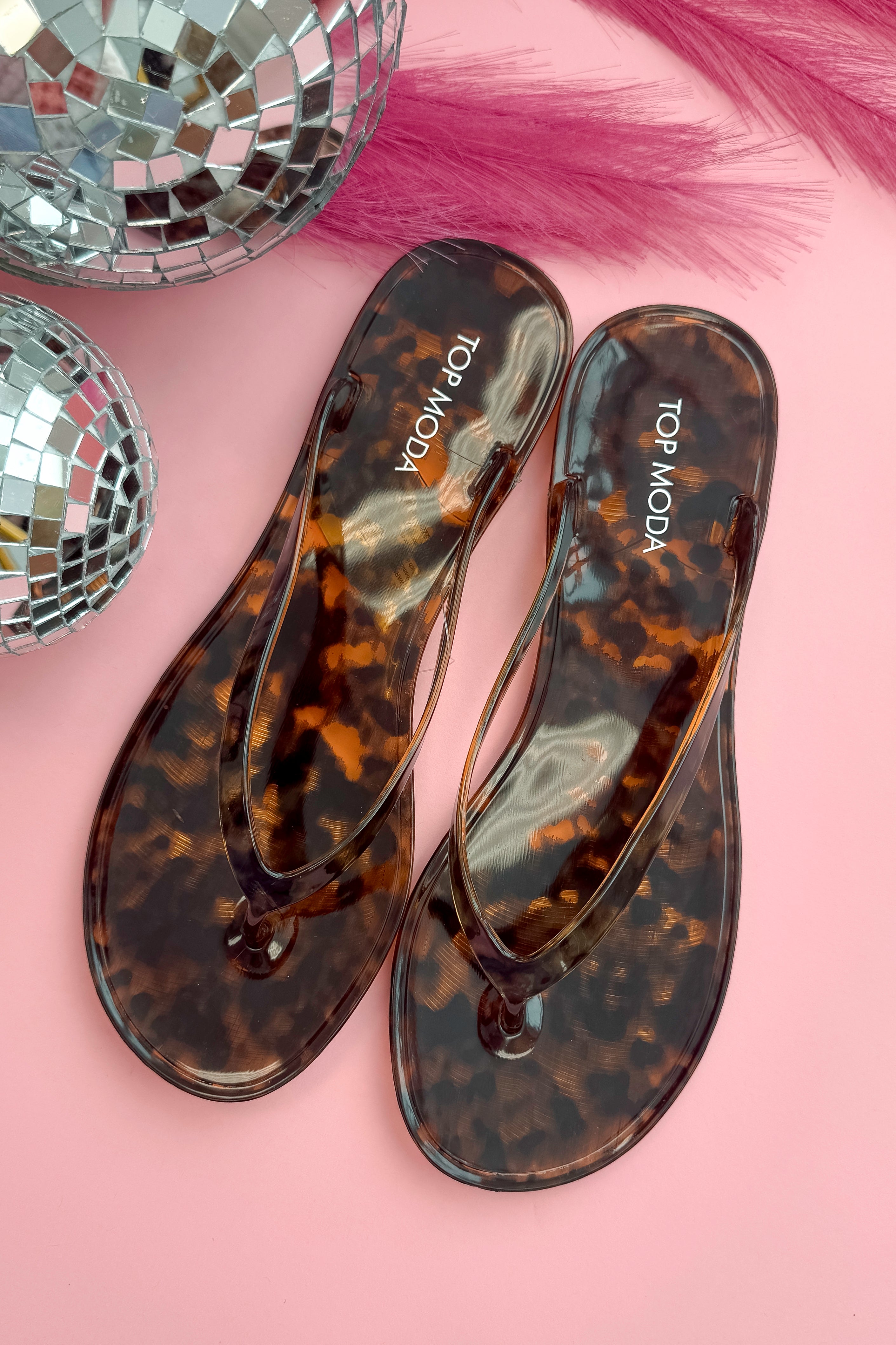 Kate- Tortoise Flip Flops against a pink background