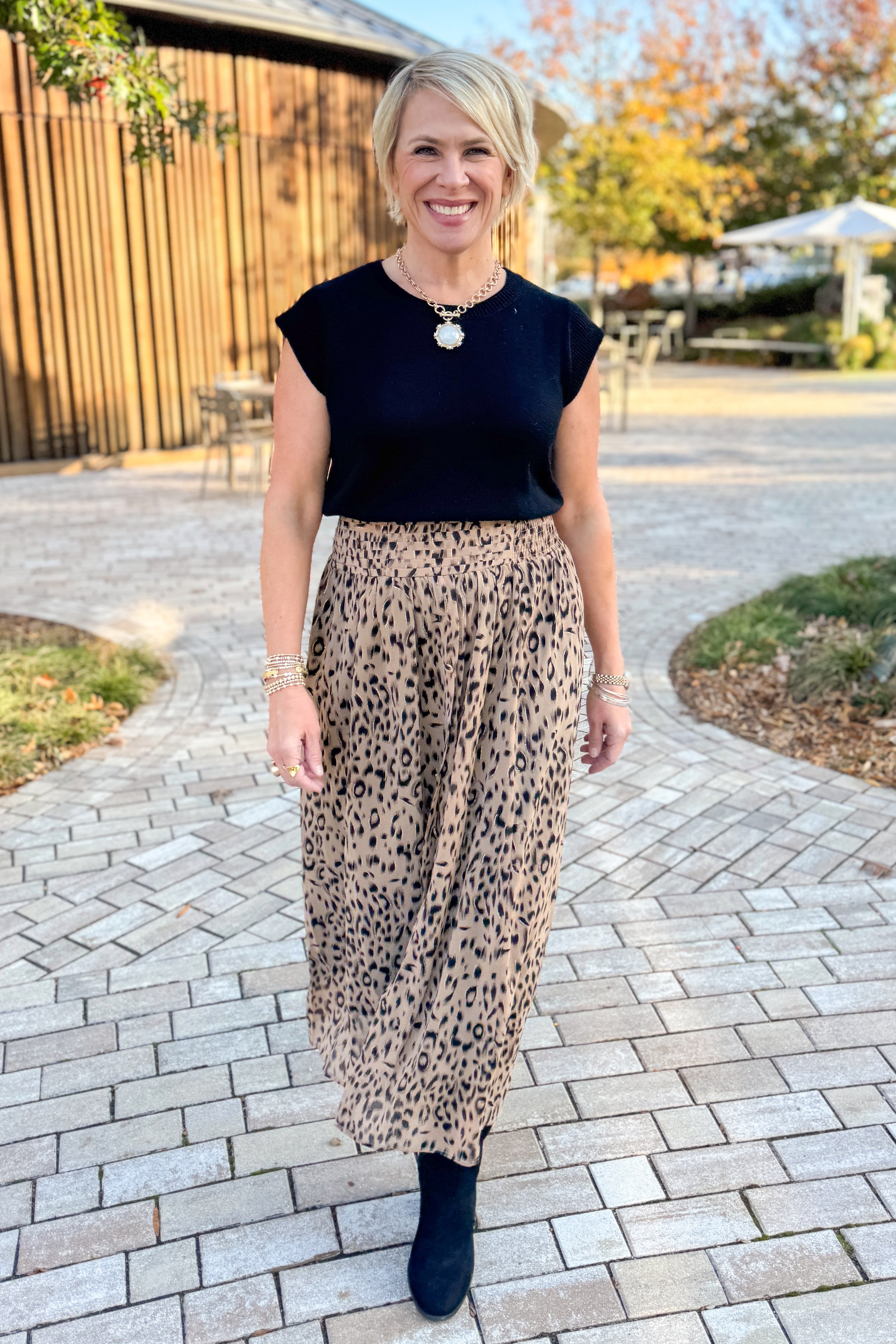 Front view of woman wearing black sweater with Beige Leopard Button Detail Skirt outside.