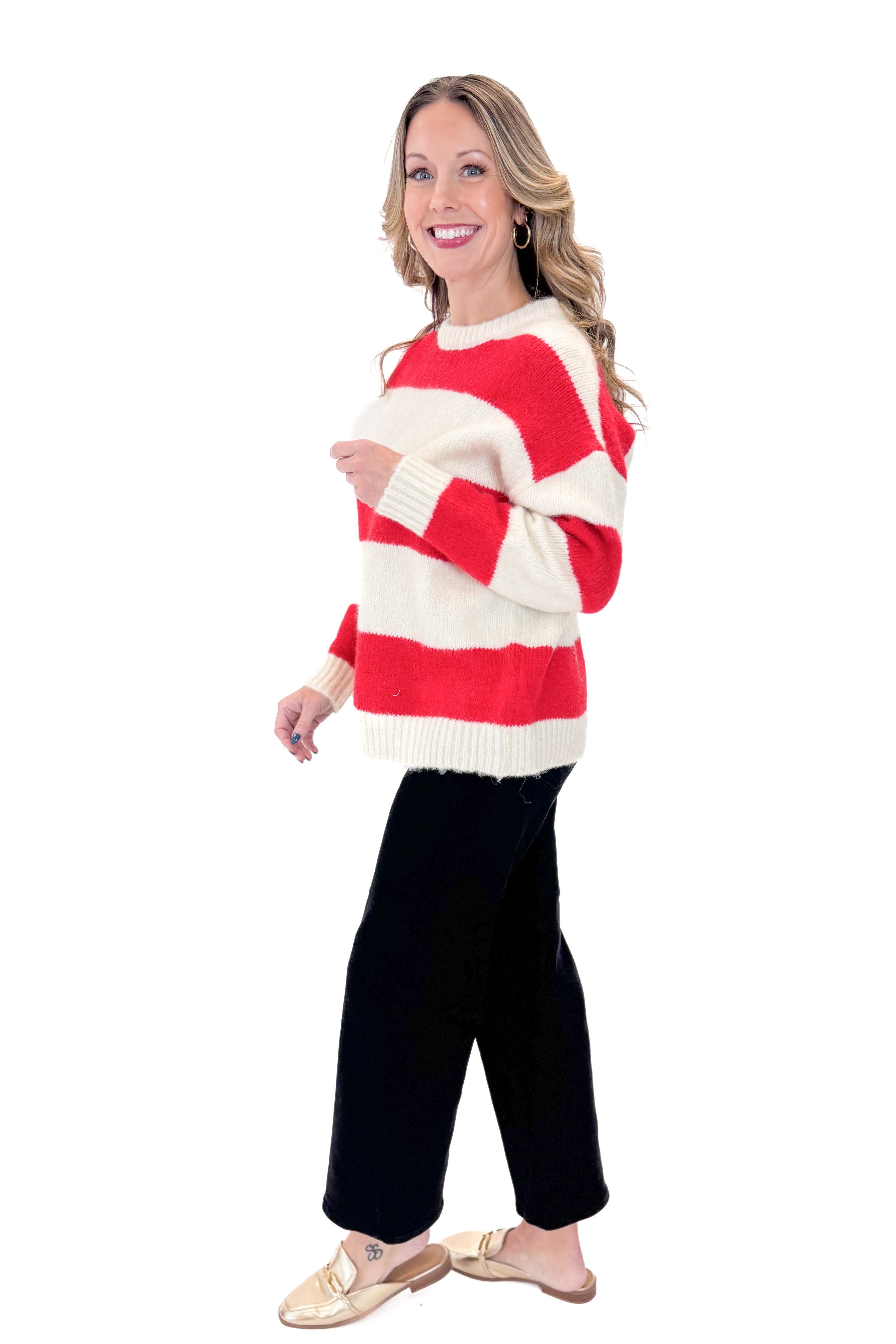 Side view of woman wearing Ivory & Red Striped Sweater with jeans against white studio background.