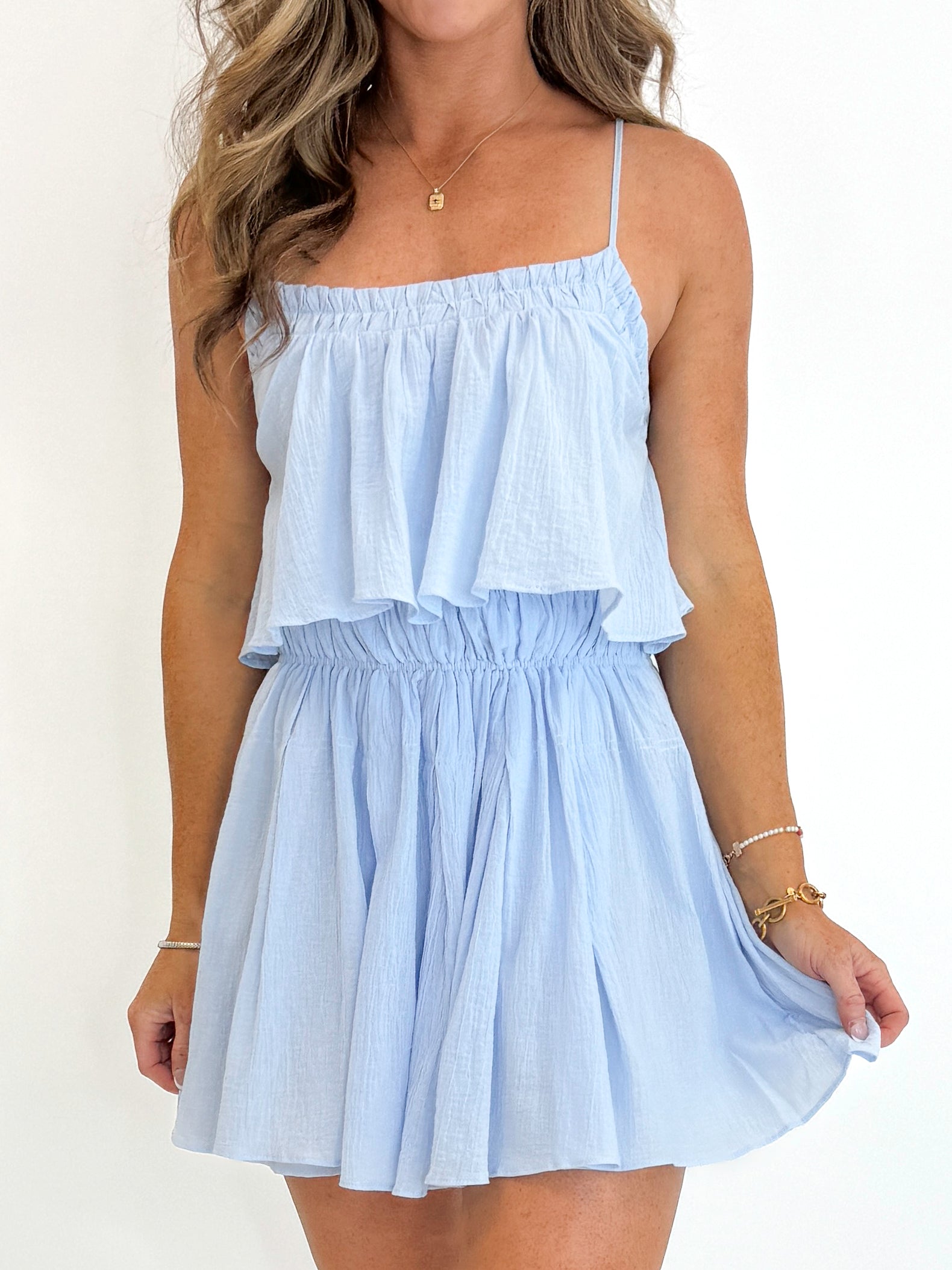 Front detail view of woman wearing Swagger Boutique’s Light Blue Pleated Mini Dress against white studio background.