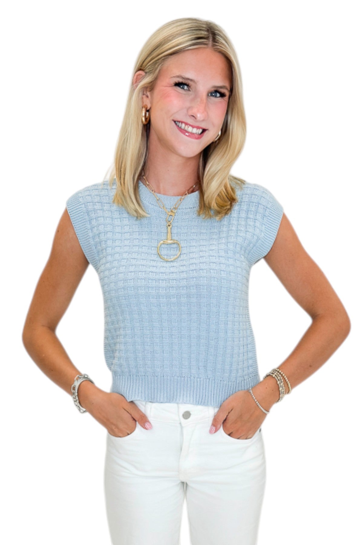 Front view of woman wearing Swagger Boutiqueās Light Blue Textured Sleeveless Sweater with jeans against white studio background.